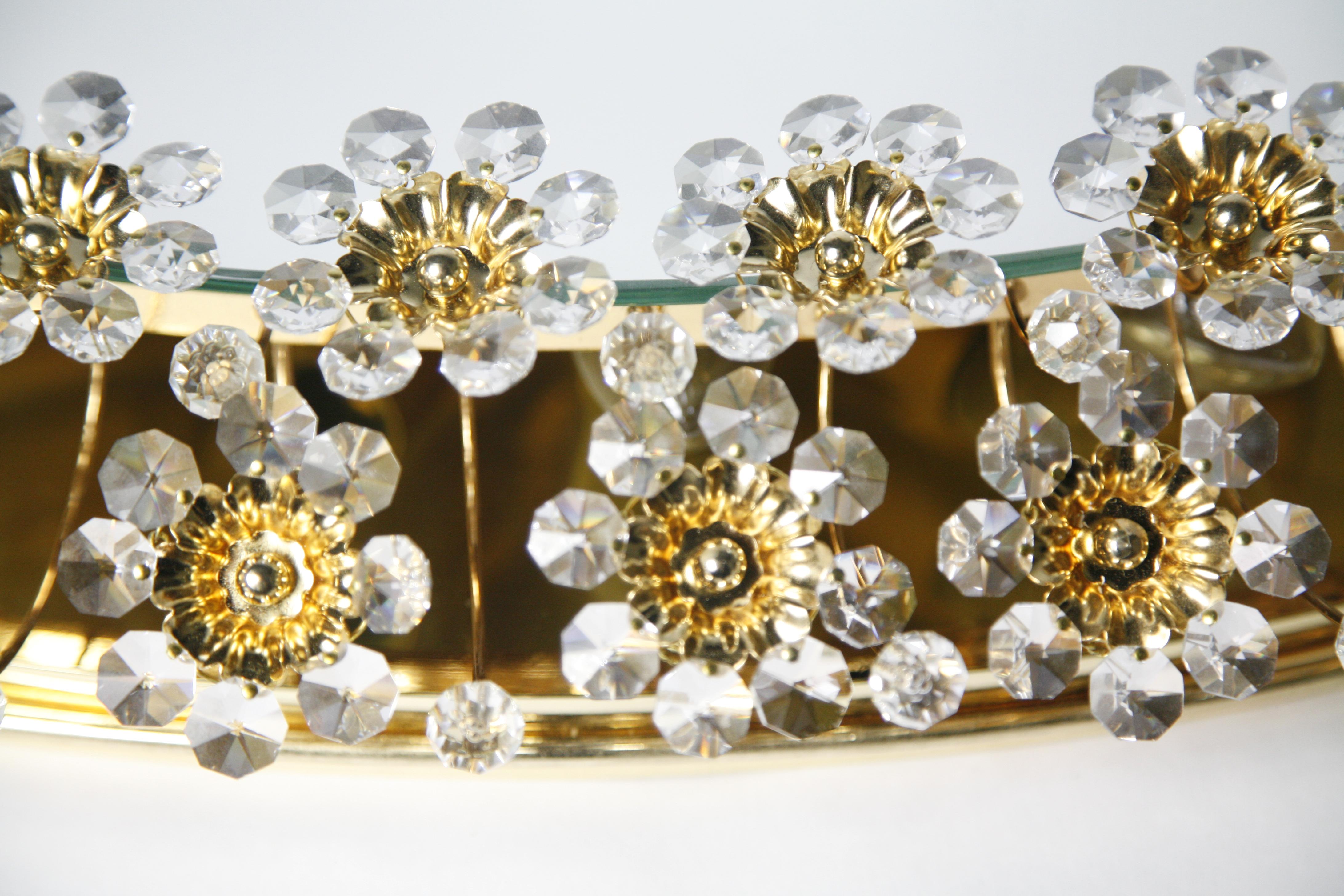 Milieu du XXe siècle 1970 Miroir Palwa en forme d'ellipse Cadre plaqué or 24 carats entouré d'ornements en cristal taillé en diamant avec de nombreux cristaux taillés et perles de cristal par Swarovski cristaux Autriche.
Ce miroir est rétroéclairé