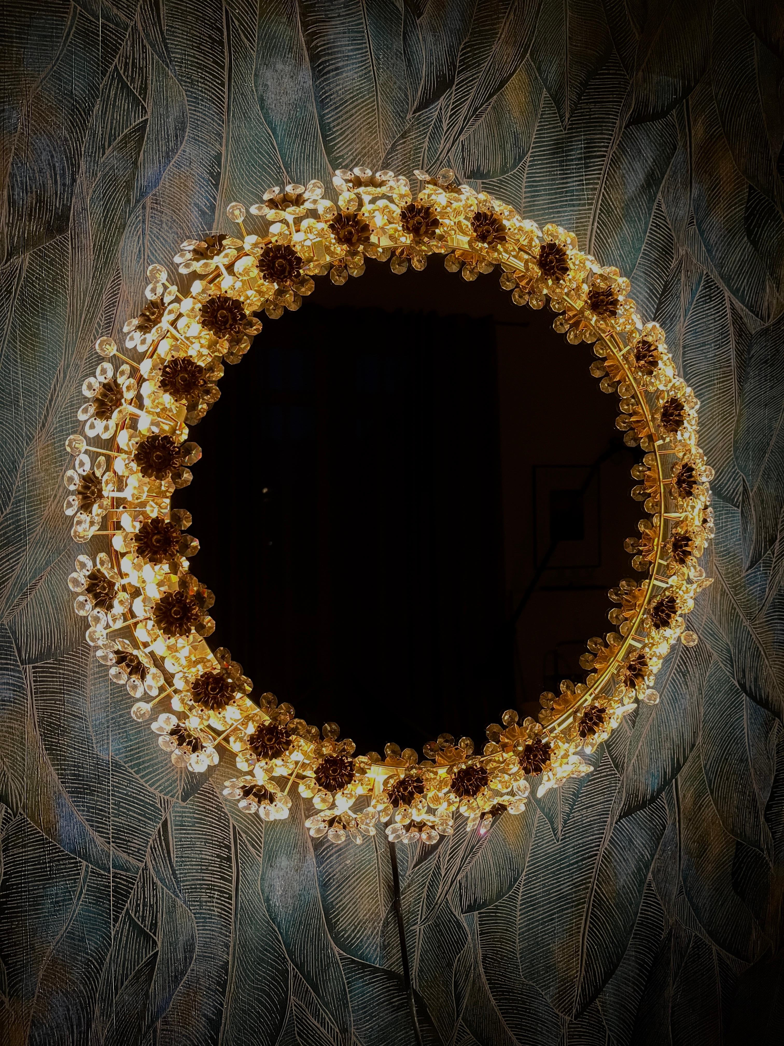 A round wall mirror by Palme & Walter with indirect lighting and crystal flowers from the 1970s.
Absolutely high-quality workmanship! The brass frame is gold-plated and the flowers are made of crystal. All crystals are present!

This vintage item is