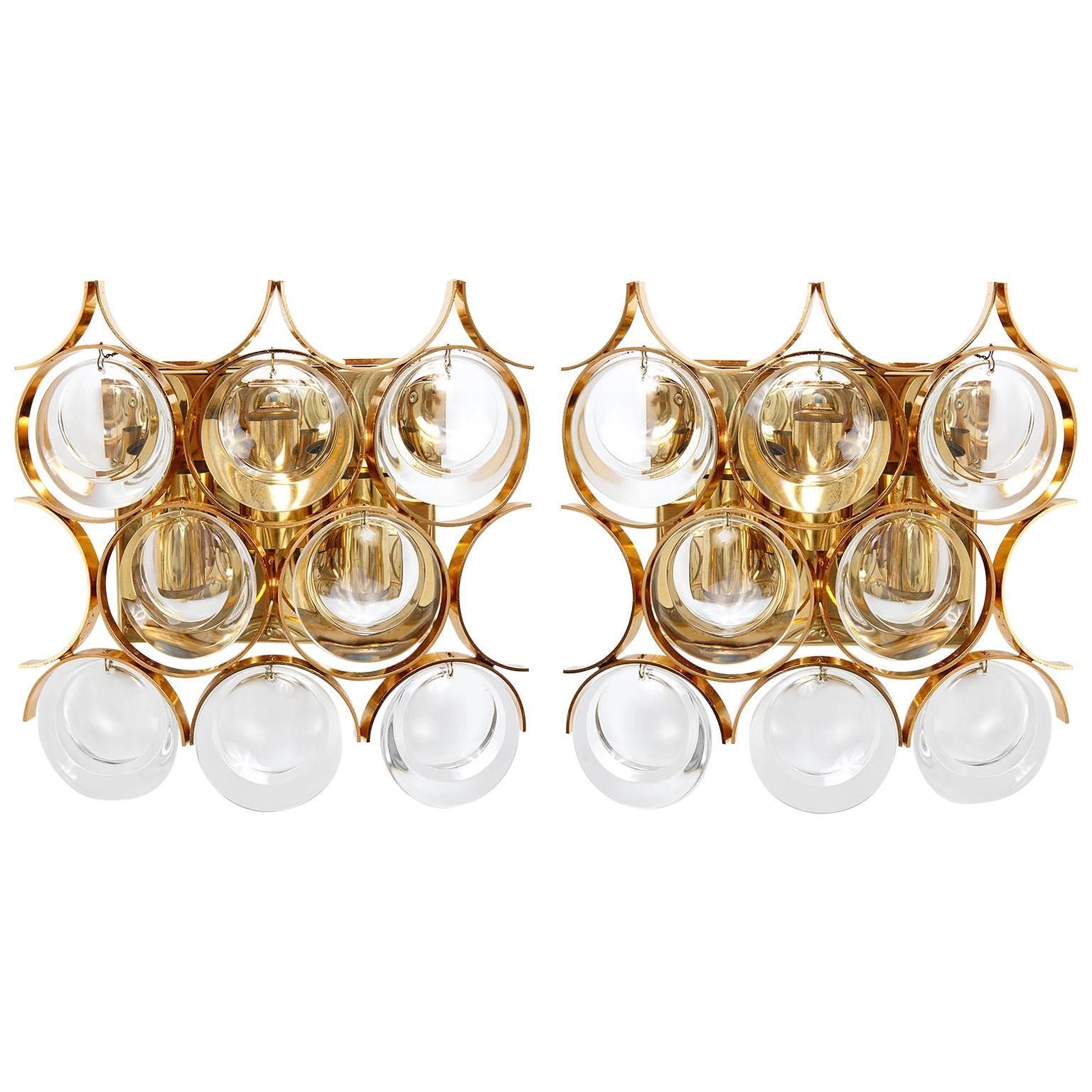 One of four wall lights by Palwa (Palme and Walter), Germany, manufactured in midcentury, circa 1970 (1960s-1970s). They are made of gilded or gilt or gold-plated brass and large round lens glasses. Each lamp takes three small screw base bulbs (type