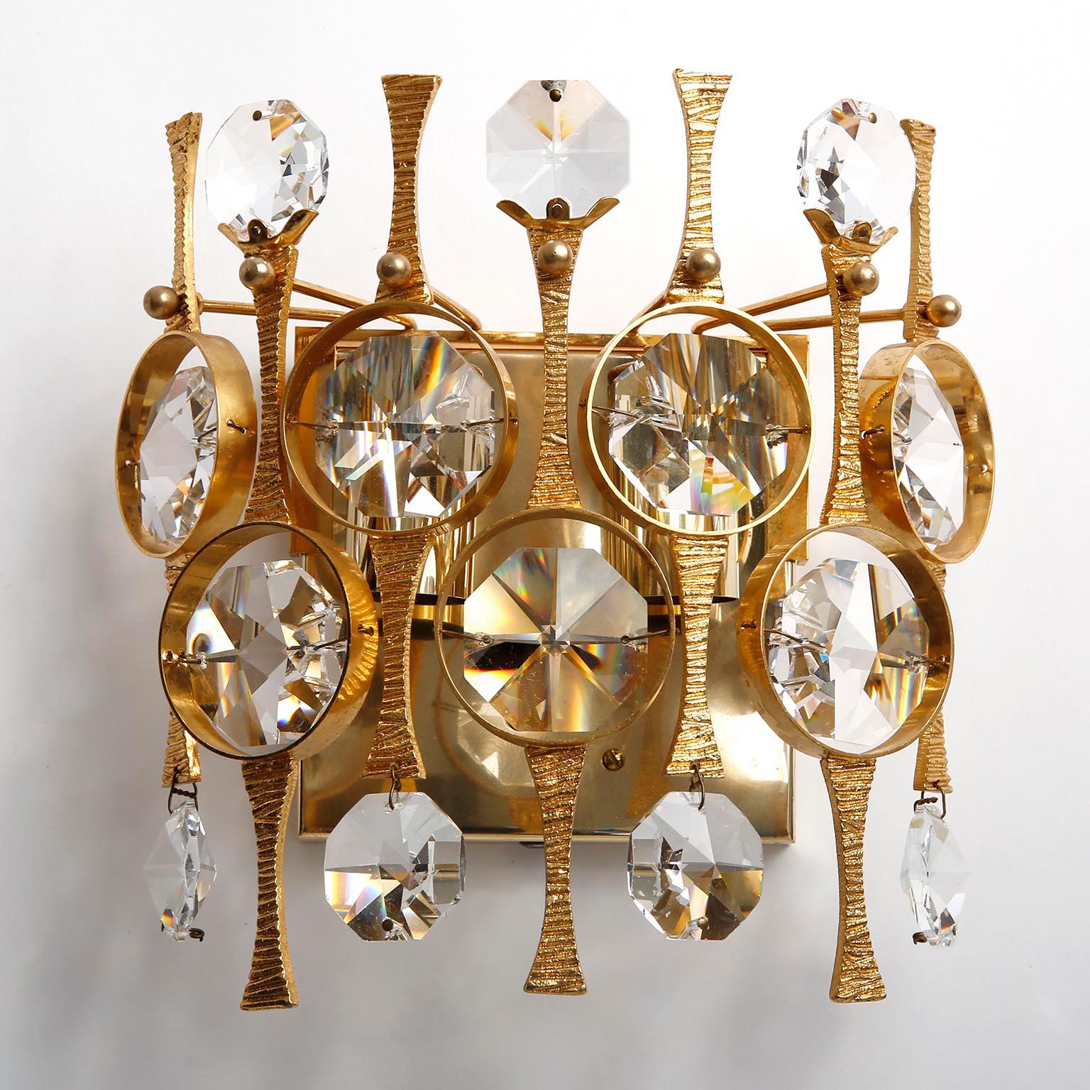 A pair of beautiful wall light fixtures by Palwa (Palme and Walter), Germany, manufactured in midcentury, circa 1970 (late 1960s or early 1970s). They are made of a gilded / gilt / gold-plated brass frame which is decorated with cut crystal glass