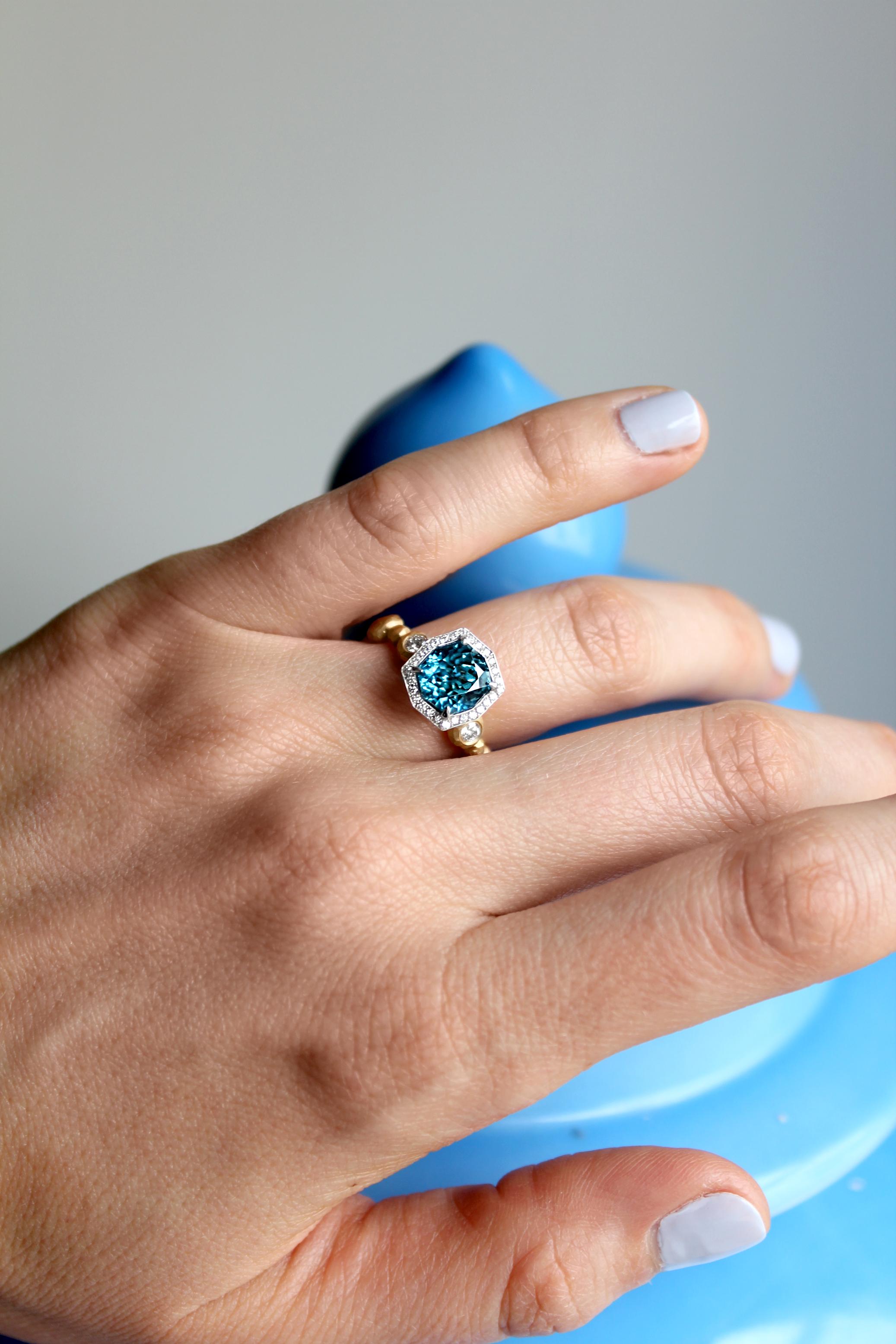 Crush Ring handcrafted by award-winning jewelry designer Pamela Froman in intricately-finished 18k yellow gold showcasing a spectacular natural 4.28 carat fancy-cut Cambodian blue zircon surrounded by a round brilliant-cut white diamond bezel in 18k