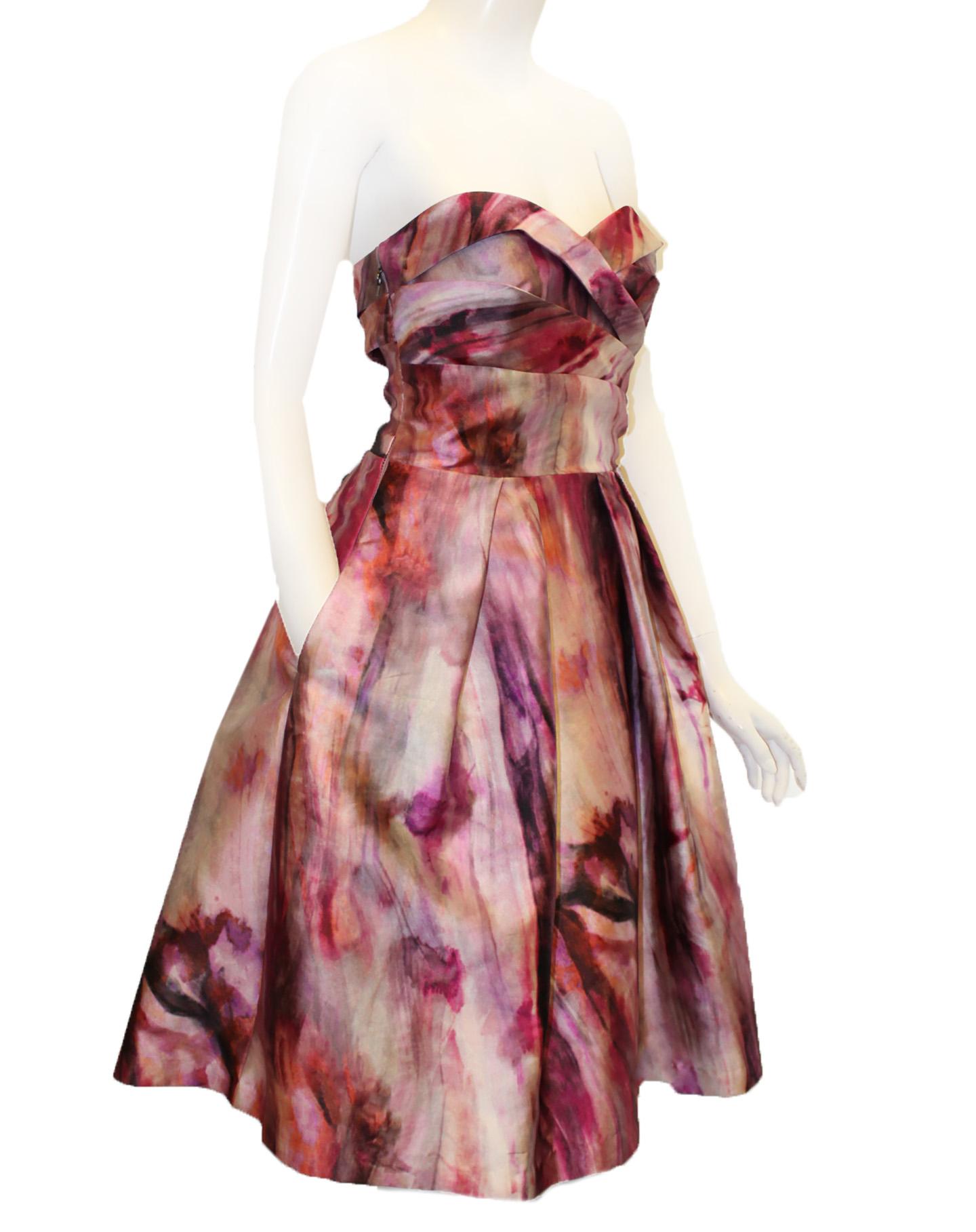 Pamella Roland pink and lavender abstract floral design with criss cross sashes at bust line and creating a band at back.  Band at the back fashions a cut out down to the waist.   The skirt is pleated.  This dress is lined in lavender fabric.  This