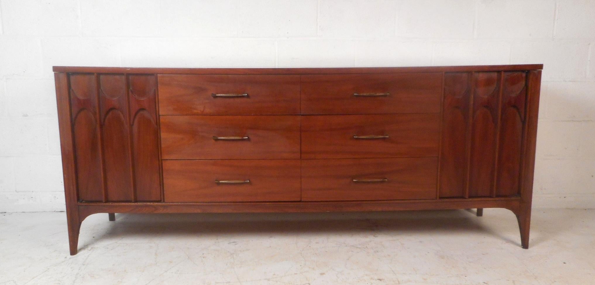 A gorgeous Mid-Century Modern walnut credenza with sculpted rosewood fixtures on the cabinet fronts. This stylish credenza features six large drawers in the centre and six drawers hidden behind cabinet doors on each side. A straight line design with