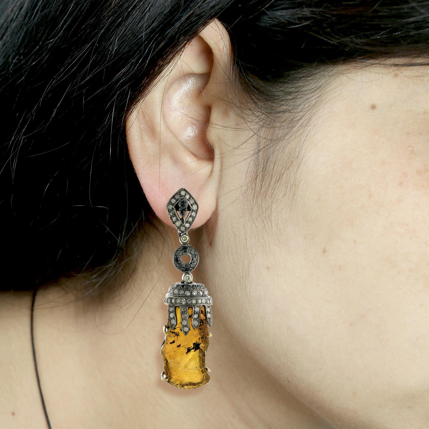 The earring features a pampel shaped tourmaline gemstone, which has a distinctive elongated pear shape. The tourmaline is a vibrant, colorful gemstone that comes in a range of shades, including pink, green, and blue. The earring also includes pave