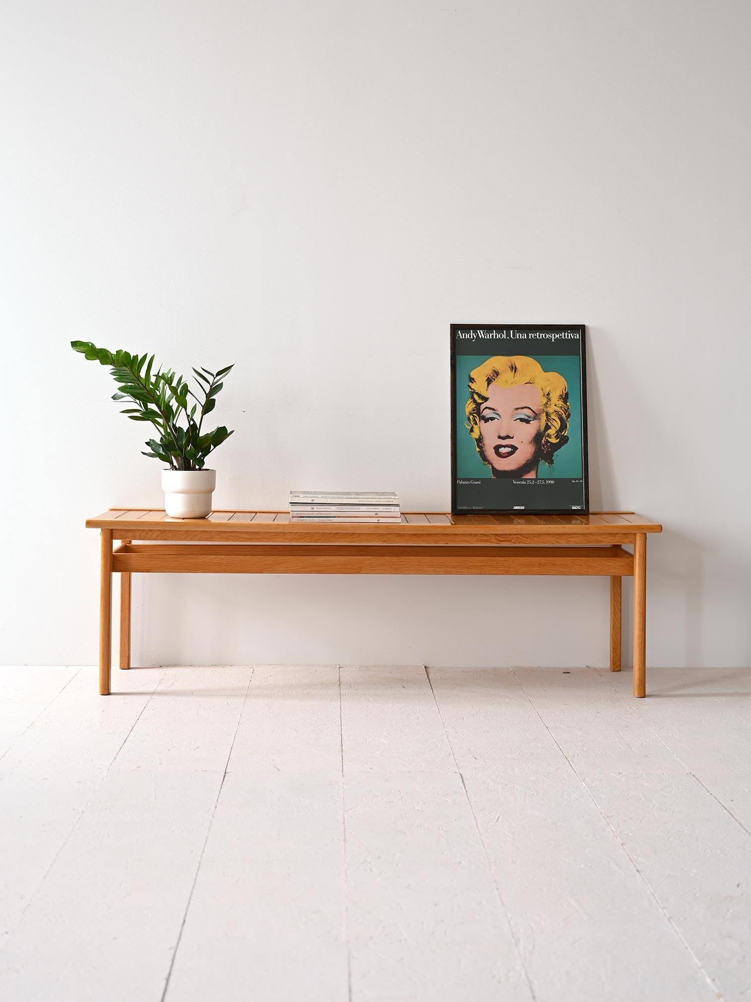Vintage 1960s Danish-made oak bench with minimalist design.

This piece of furniture boasts a sleek, minimalist design with a table top composed of teak wood slats, supported by square legs. It can be used in various spaces in the home to create the