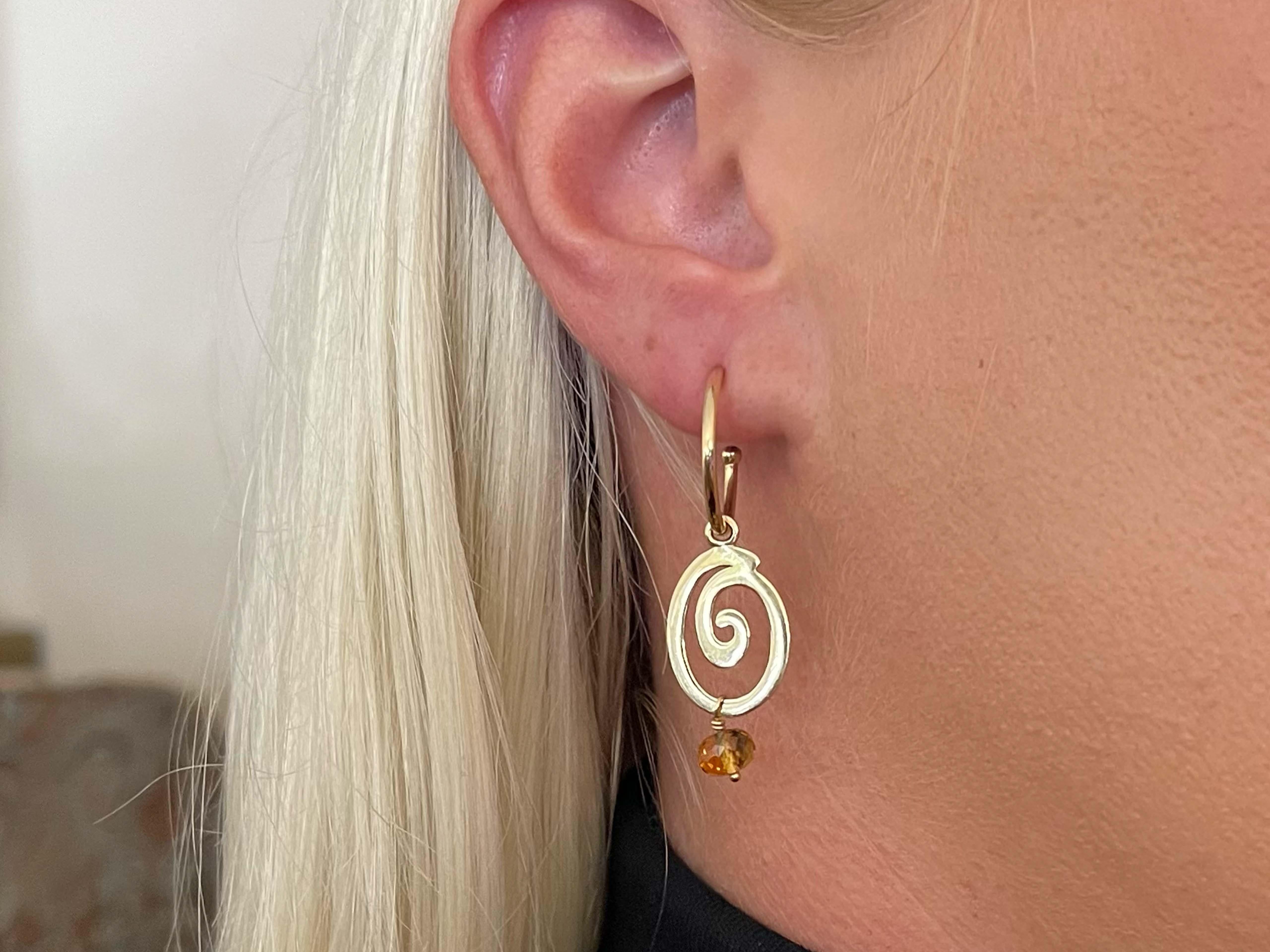 Diese stilvollen Ohrringe sind mit einem facettierten gelben Stein versehen, der an einem Wirbeltropfen baumelt. Die Ohrringe sind 1,5