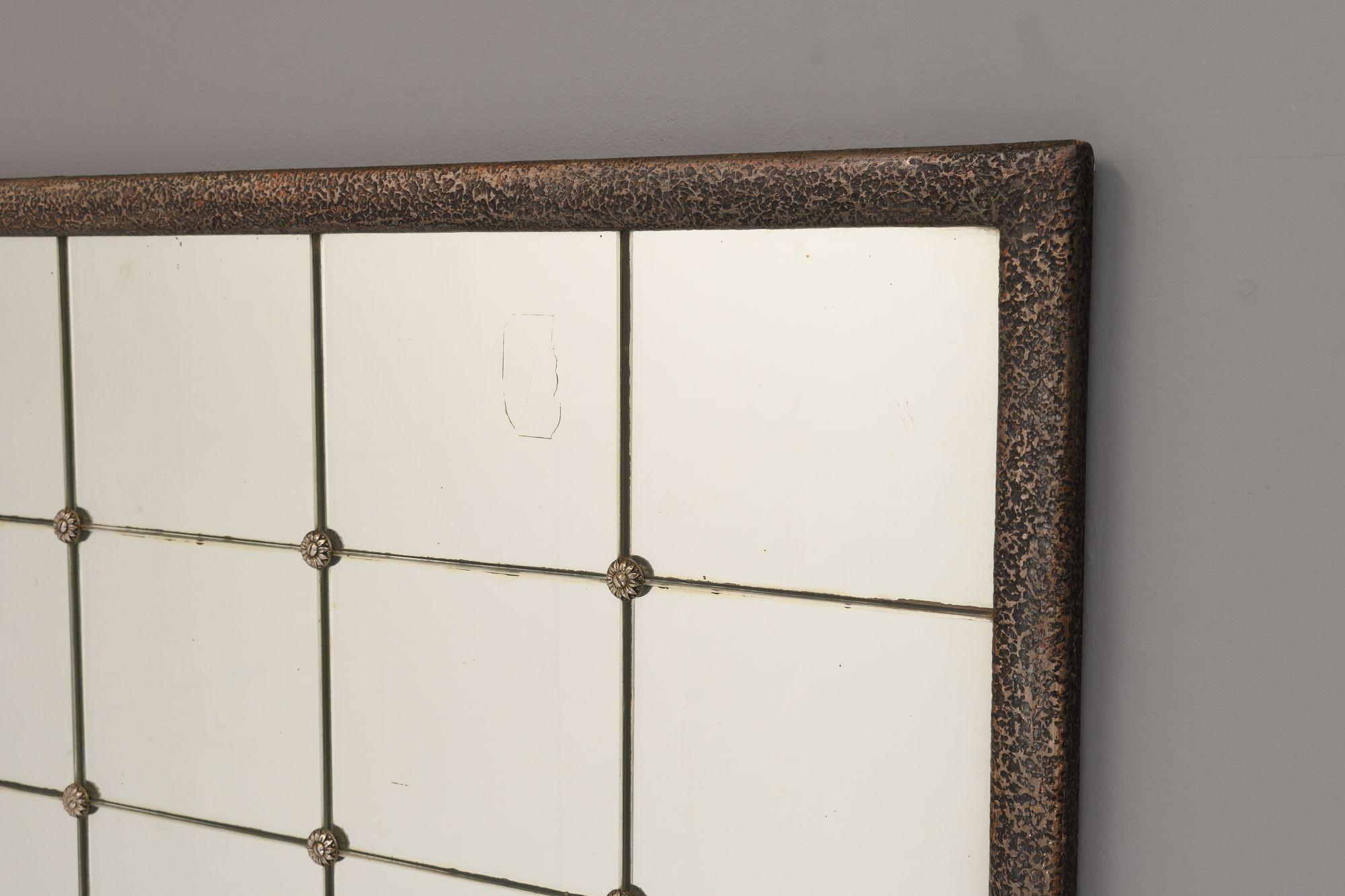Miroir rectangulaire du début du 20e siècle avec cadre en plâtre texturé. 12 panneaux de miroir carrés d'origine maintenus en place par des boutons floraux argentés. Circa les années 1920.

H 56cm x L 81cm x P 3cm