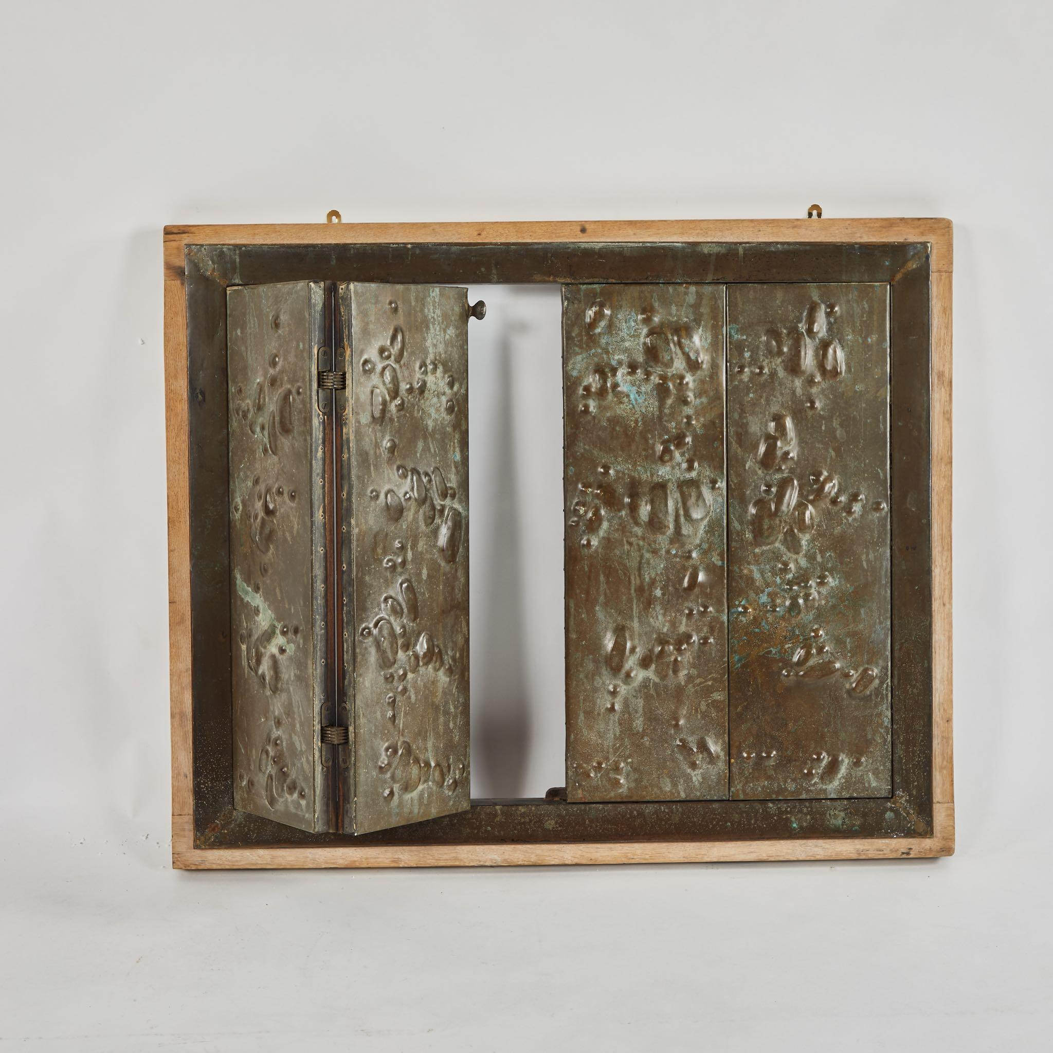A panel on hinges in metal, originating in England, circa 1910.