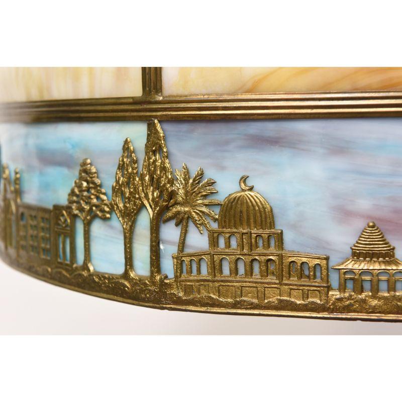 Panel shade with Brown and blue slag glass. Three light cluster. Arabic style motif with palms and buildings. American, C. 1920. Completely restored and rewired.

Dimensions: 
Height: 25