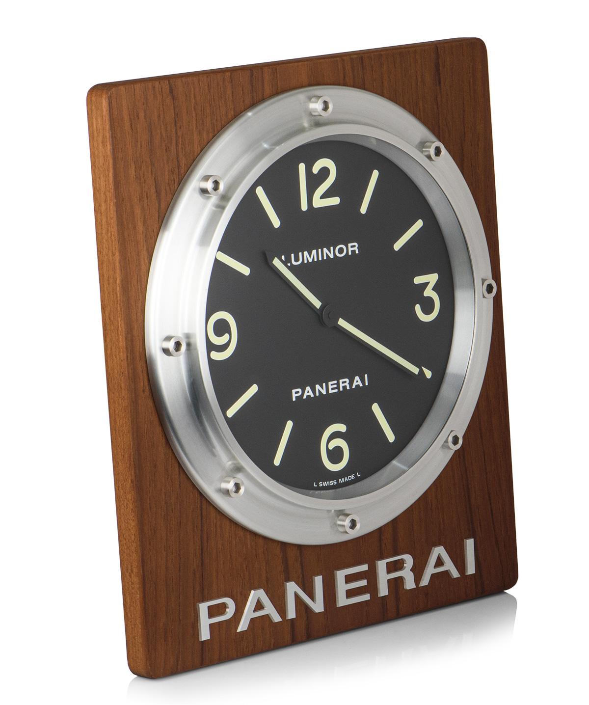 A 290 mm Aluminium & Wood Wall Clock, black dial with hour markers and arabic numbers 3,6, 9 and 12, a fixed aluminium bezel, a solid wooden case, plastic glass, quartz movement, in excellent condition, comes complete with a Panerai box and Undated