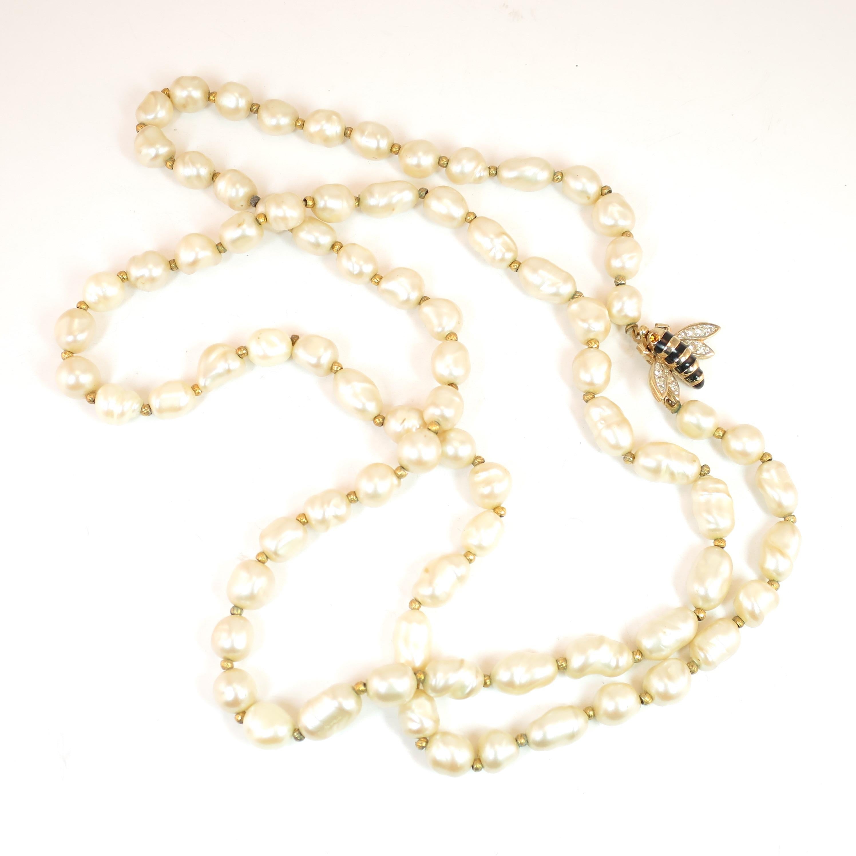 Offered here is a long Panetta faux baroque pearl necklace with a gilded and enameled bee clasp, from the 1950s. There is a single strand of iridescent cream-colored glass baroque pearls, separated by tiny gold-plated seed beads; it is finished with