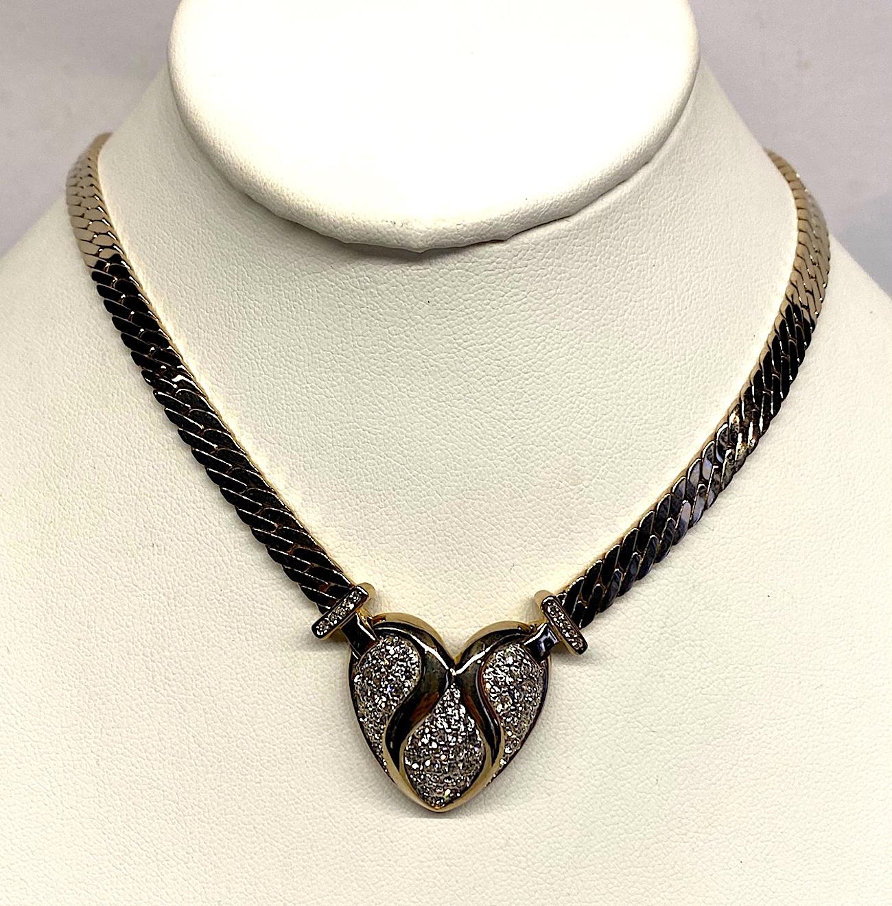 A lovely vintage heart pendant necklace by quality jewelry company Panetta circa 1980. The necklace is comprised of two gold plate flat curb link strands that meet in the center at a pave' rhinestone set heart. The heart is 1 inch wide and high in