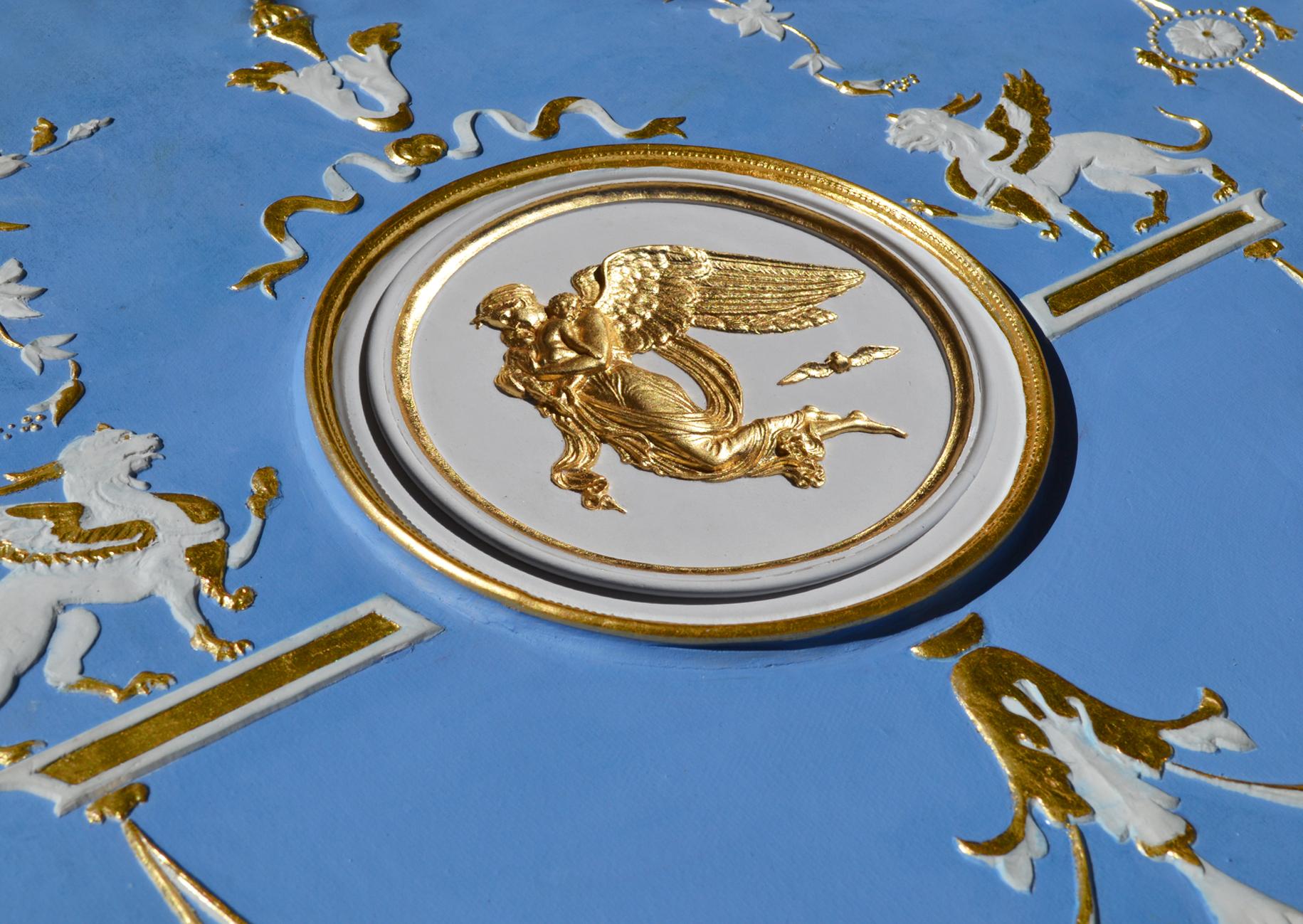 Pannello decorativo da parete azzurro con rilievi bianchi e oro, fatto a mano in Italia da Cupioli.

Elegante pannello decorativo da parete, realizzato interamente a mano, ispirato alle iconiche ceramiche Wedgwood. Il fondo azzurro delicato è