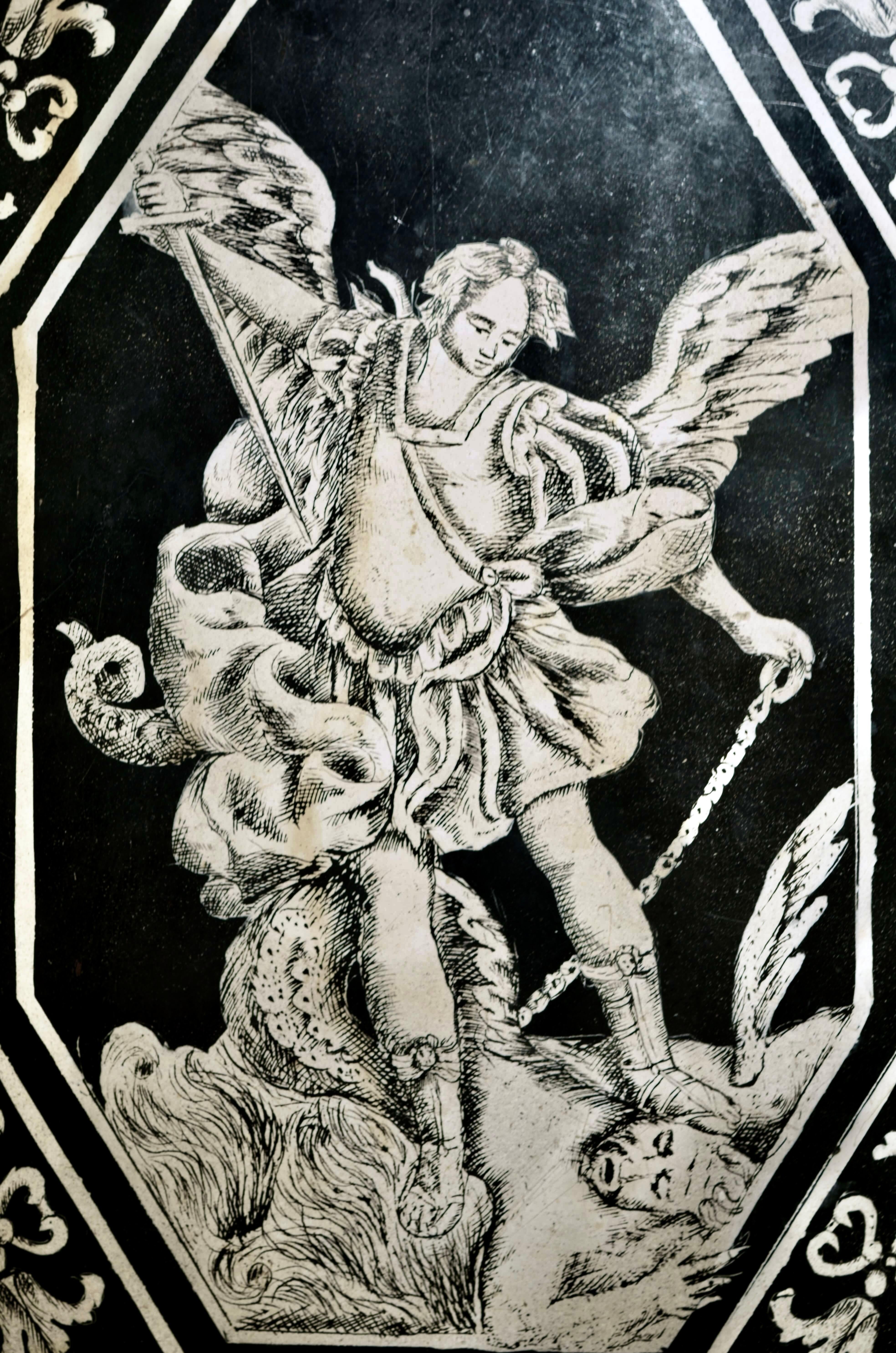 Carpi, metà del XVII secolo, pannello in scagliola.

La tavola, in bicromia bianca e nera, presenta inserimenti di elementi policromi marmorizzati e una scena centrale raffigurante San Michele che sconfigge il diavolo.
Il motivo decorativo si ispira