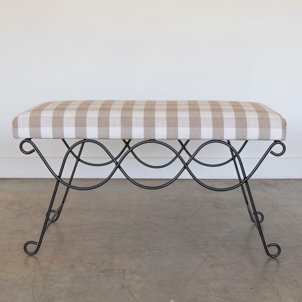 Beautiful iron bench with curved and looped base painted in a matte black finish inspired by French design. Rectangular cushioned seat upholstered in a tan gingham linen fabric or can be COM. Inquire for current lead time. Made in Los Angeles. 