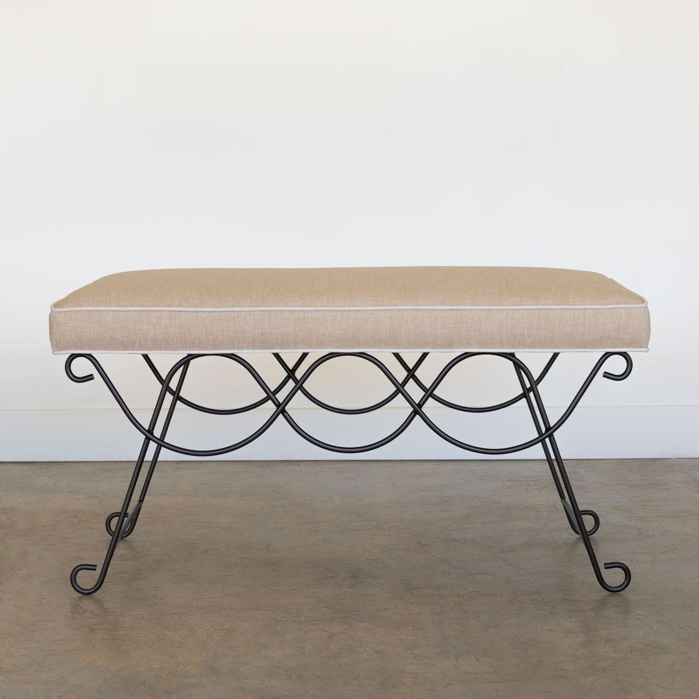 Beautiful iron bench with curved and looped base painted in a matte black finish inspired by French design. Rectangular cushioned seat upholstered in a tan cotton linen blend fabric with cream trim.  Can also be COM. Multiple available, sold