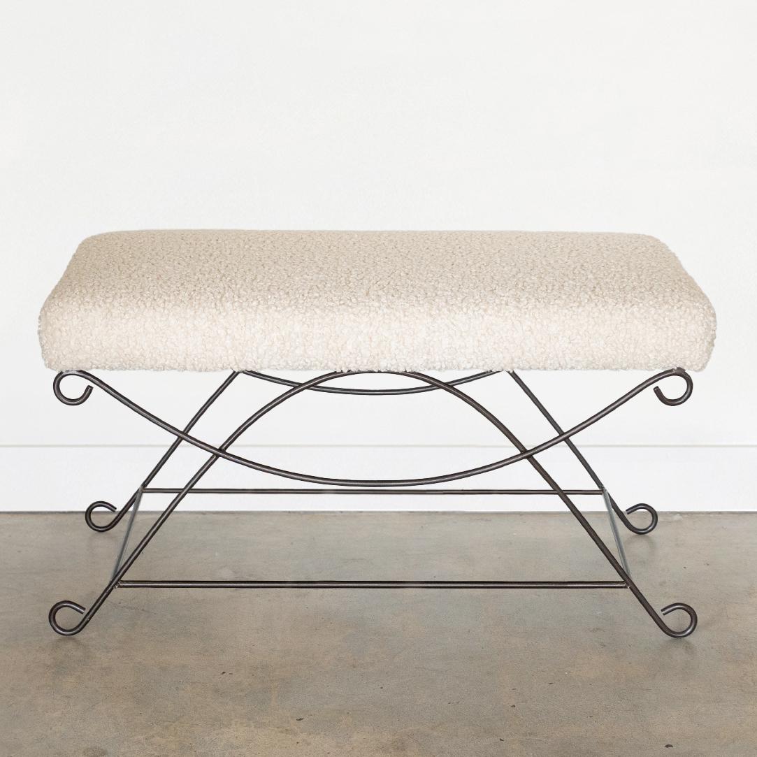 Beautiful iron bench with curved and looped base painted in a matte black finish. Rectangular cushioned seat upholstered in a creamy poodle fabric or can be COM. Multiple available, sold individually.