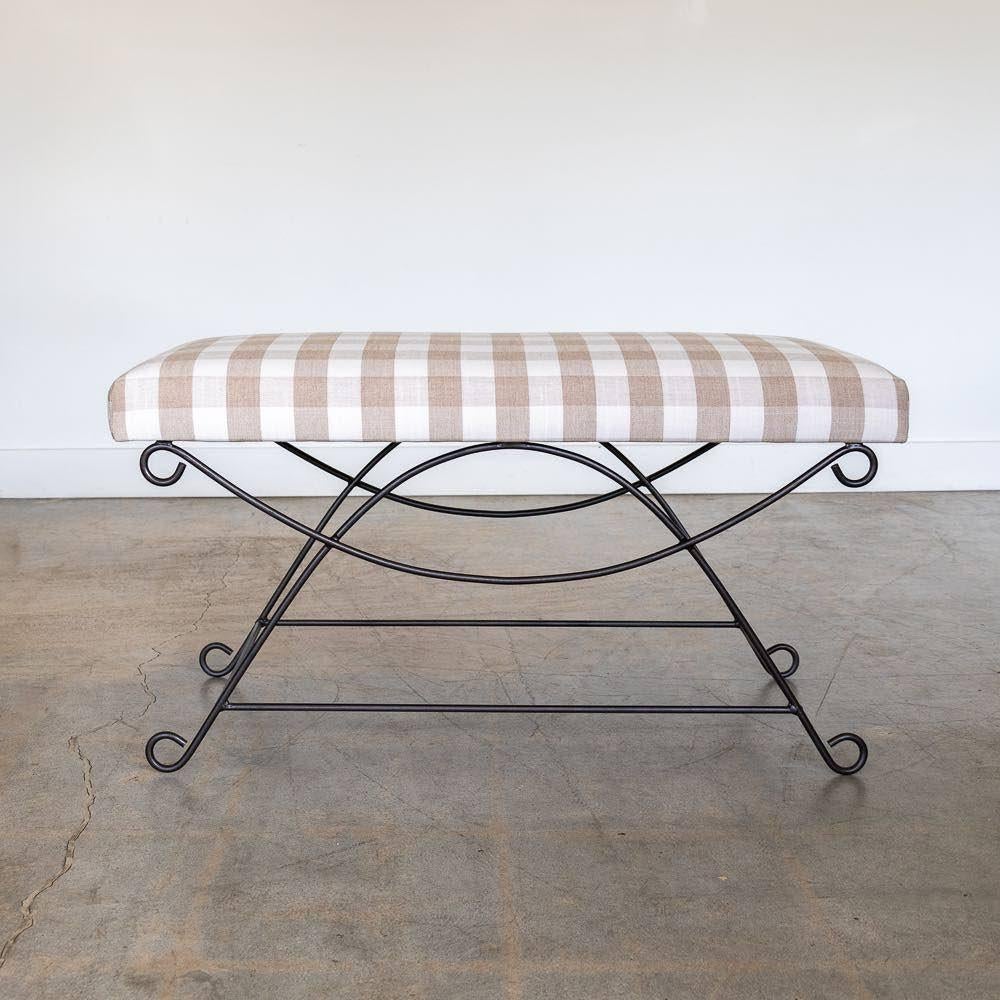 Beautiful iron bench with curved and looped base painted in a matte black finish inspired by French design. Rectangular cushioned seat upholstered in a tan gingham fabric or can be COM. Multiple available, sold individually. Made in Los Angeles.