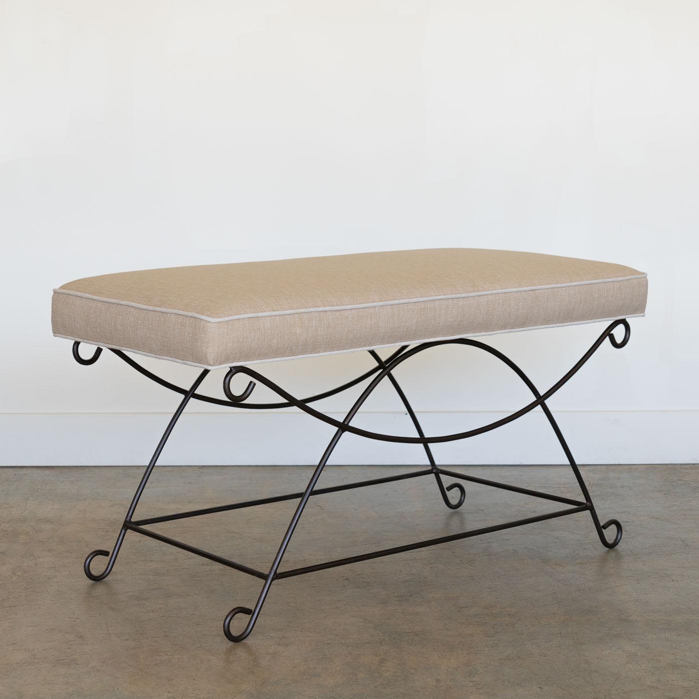 Beautiful iron bench with curved and looped base painted in a matte black finish inspired by French design. Rectangular cushioned seat upholstered in a tan cotton linen blend fabric with cream trim.  Can also be COM. Multiple available, sold