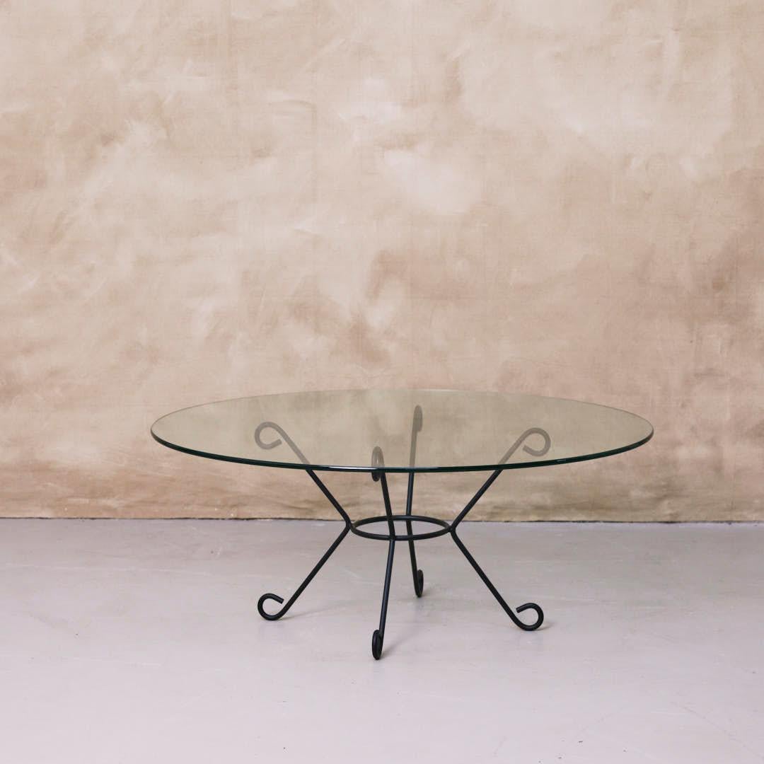 Magnifique table basse en fer et en verre inspirée du design français. Base incurvée et Looping, revêtue de poudre dans une finition noire mate avec un plateau rond en verre. Disponible en plusieurs exemplaires, vendus individuellement. Fabriquée à