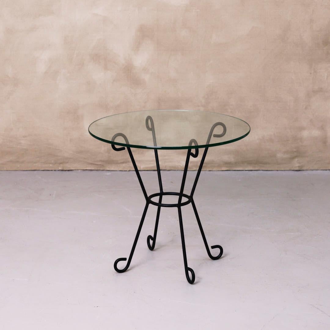 Beautiful iron and glass side table inspired by French design. Curved and looped base, powder coated in a matte black finish with a round glass top. Multiple available, sold individually. Made in Los Angeles.