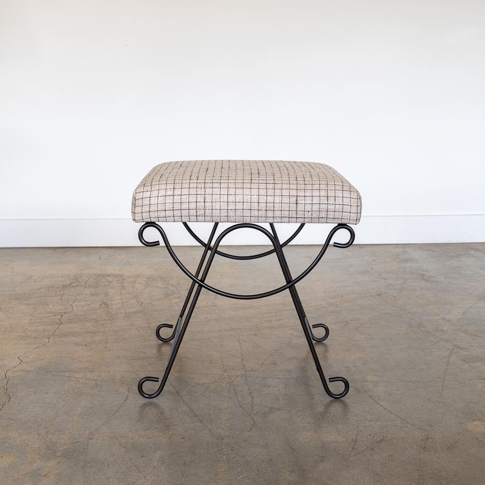 Beautiful iron stool with curved and looped base painted in a matte black finish inspired by French design. Rectangular cushioned seat upholstered in a check linen or can be COM. Made in Los Angeles.