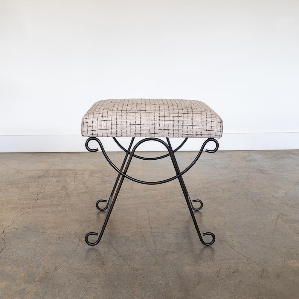 Beautiful iron stool with curved and looped base painted in a matte black finish inspired by French design. Rectangular cushioned seat upholstered in a check linen or can be COM. Made in Los Angeles.