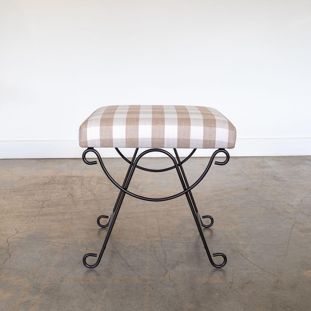 Beautiful iron stool with curved and looped base painted in a matte black finish inspired by French design. Rectangular cushioned seat upholstered in a tan gingham or can be COM. Made in Los Angeles.