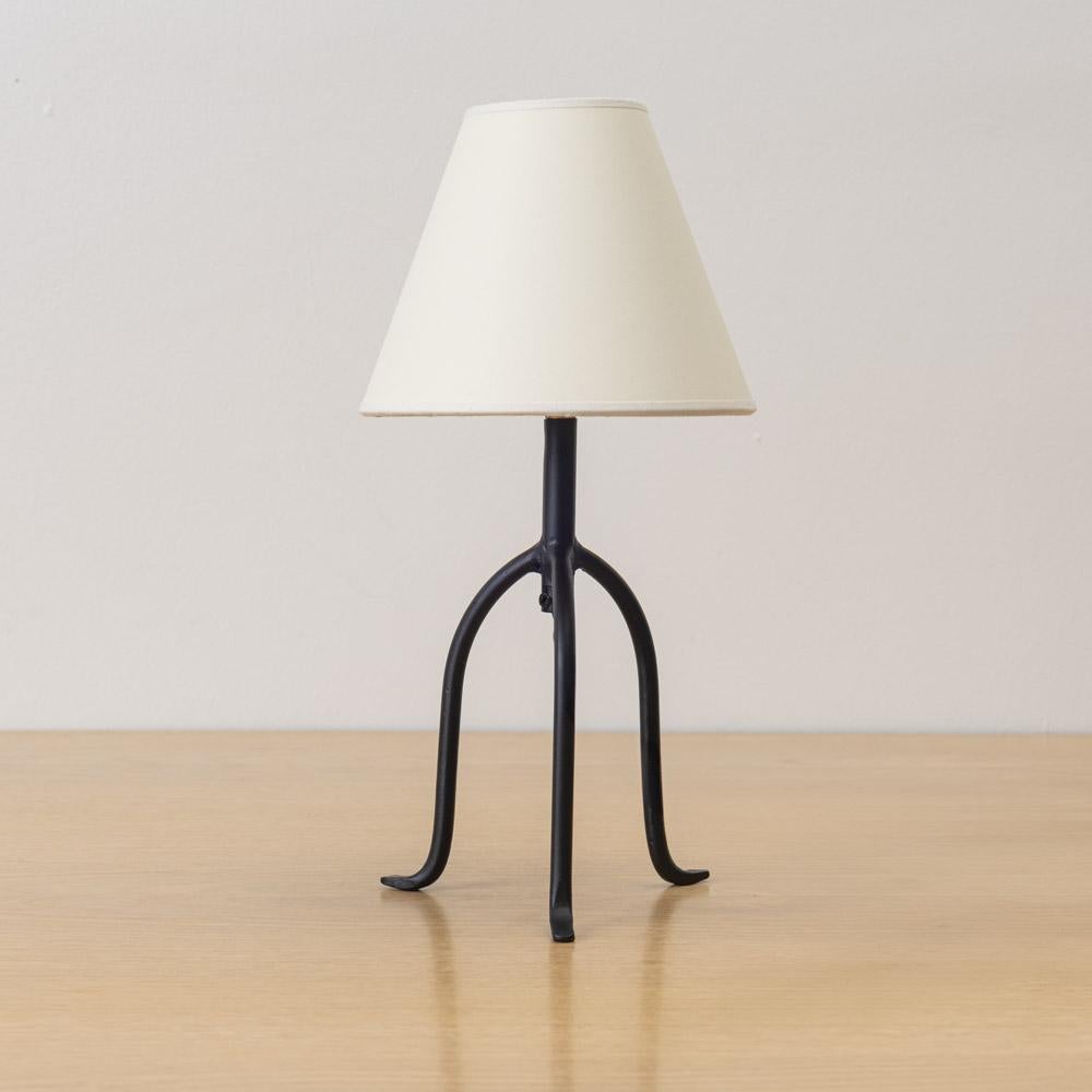 Piccola lampada a treppiede in ferro con gambe sottili e piedi affusolati. Nuovo cablaggio e nuova tonalità di pergamena. Venduti singolarmente e realizzati da Panoplie. Informati sui tempi di consegna attuali. Disponibili in più versioni, vendute