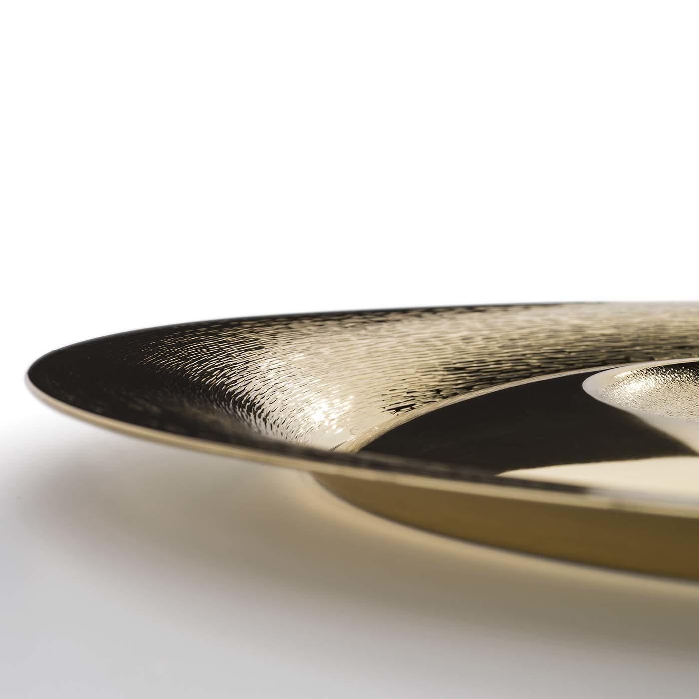 Crafted of brass with a gold-plating, this elegant bowl exemplifies traditional craftsmanship and innovative design aesthetic. The round plate features a flared rim sloping towards the center of the plate to create an undulating surface alternating
