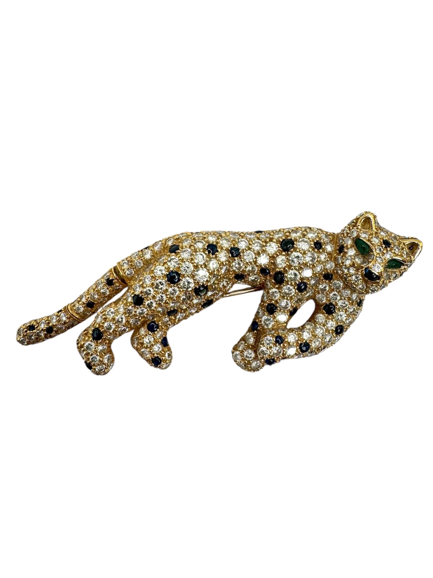 A striking embodiment of elegance and power, this panther brooch is masterfully crafted in 18K yellow gold and adorned with 312 brilliant-cut diamonds totaling approximately 10.50 carats. Scattered among the dazzling white diamonds are 52 deep blue