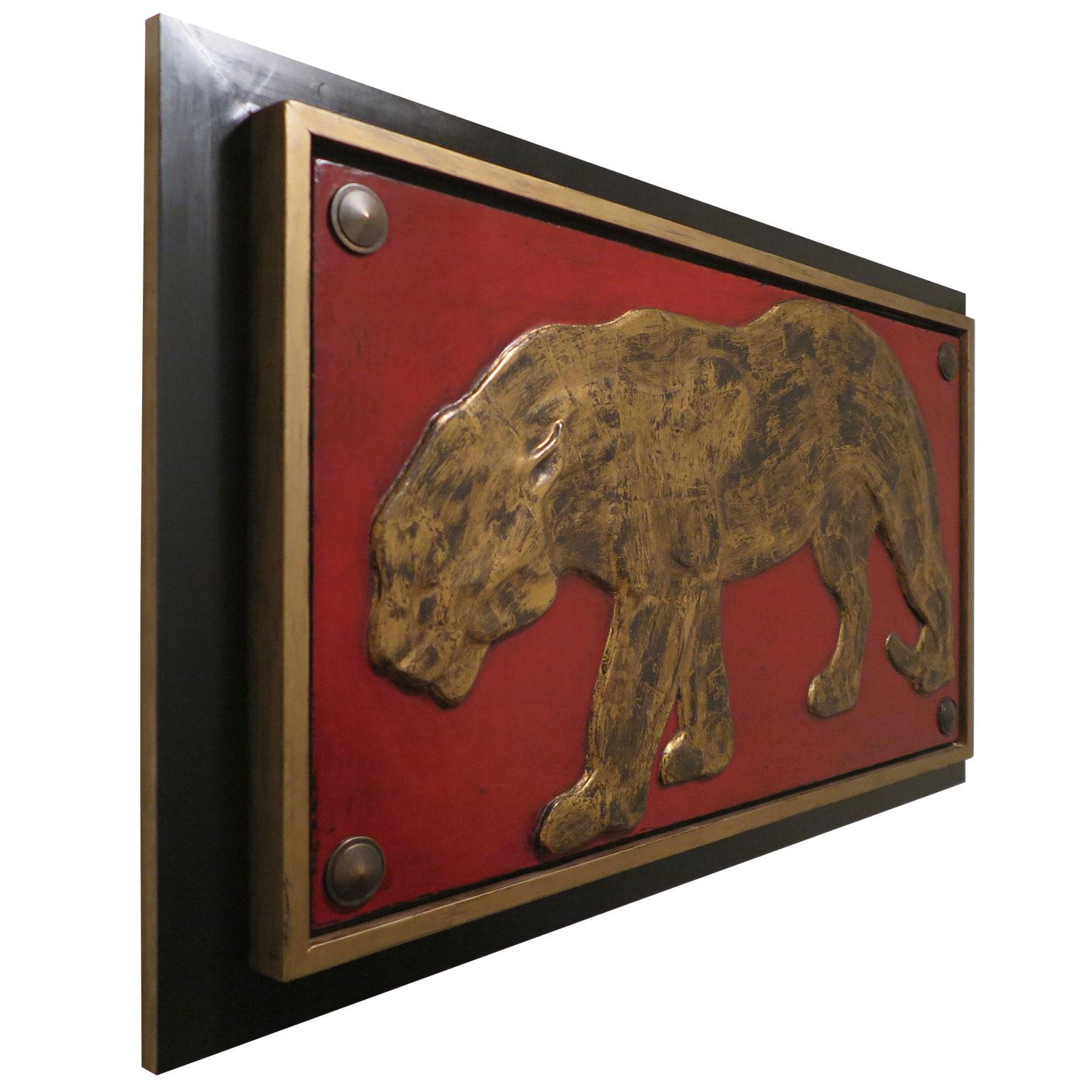 Raised relief carving of panther applied with distressed gold leaf. China red painted background with pointed pyramid style ornamentation in each corner. Gold and black matte frame.