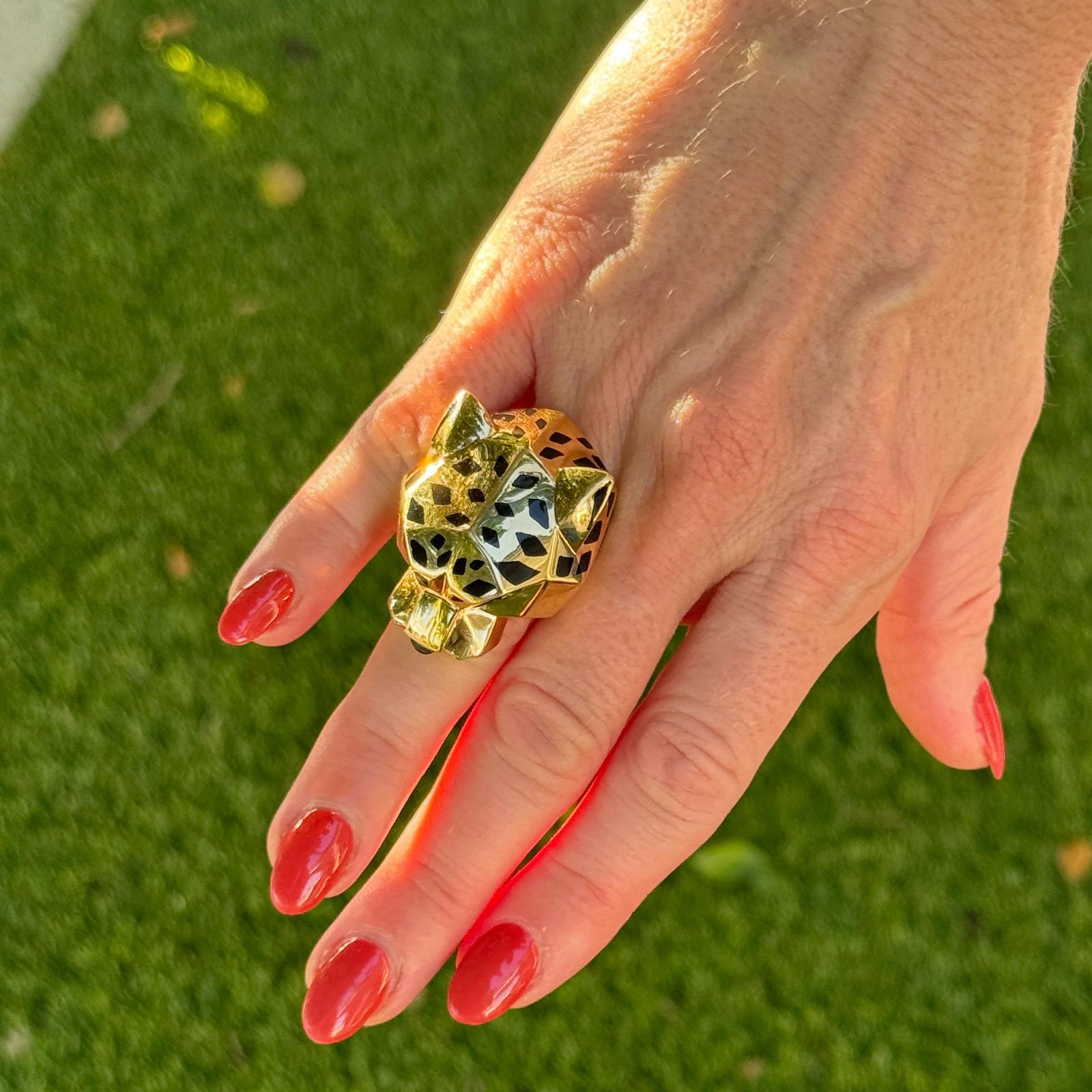 Symbole emblématique de l'élégance intemporelle de Cartier, cette bague Panthère de Cartier est réalisée en or jaune 18 carats et arbore le motif de la panthère à gueule ouverte caractéristique de la Maison. Les détails de la laque noire et les yeux