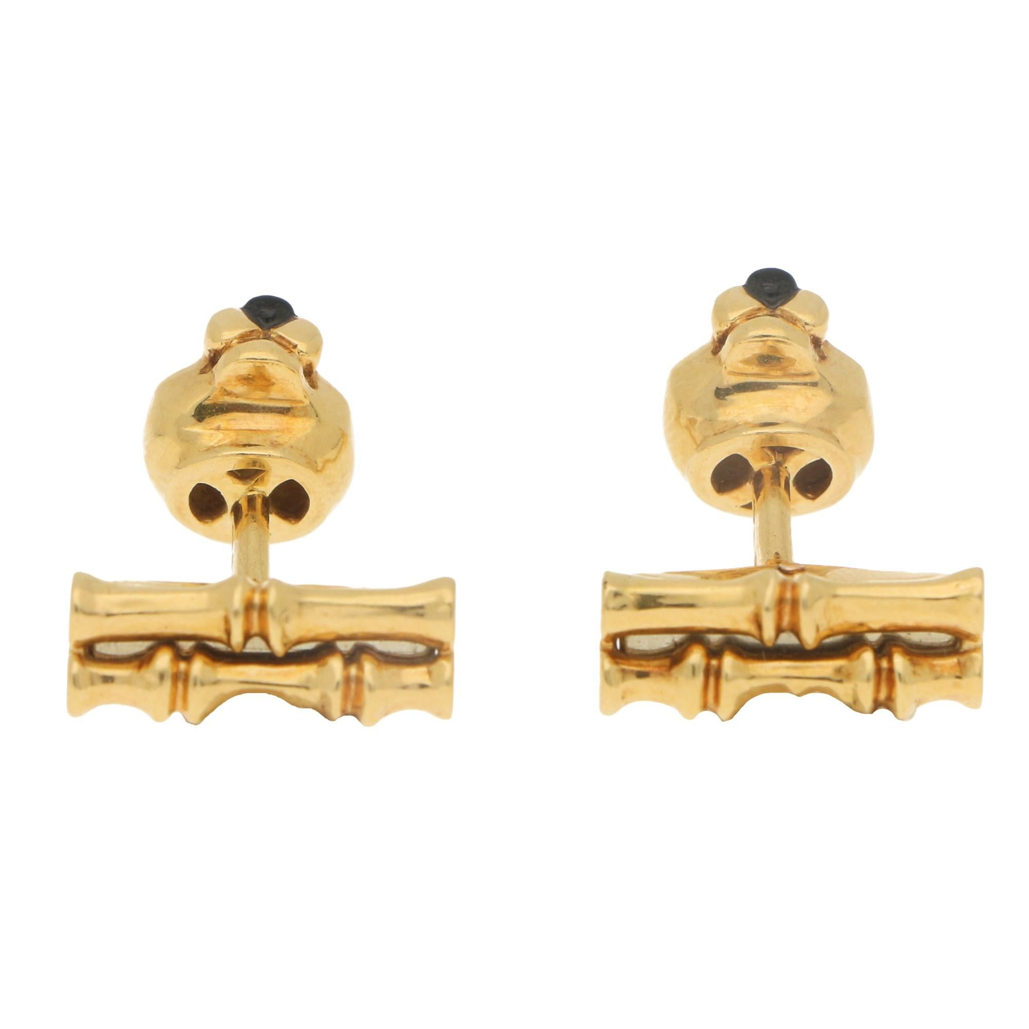 A fabulous pair of Panthère de Cartier cufflinks set in 18k yellow gold. Each cufflink features as a panthers head set with two round cut emerald eyes and a cute onyx nose. The heads are joined by a gold post to a bamboo motif swivel back bar.

Each