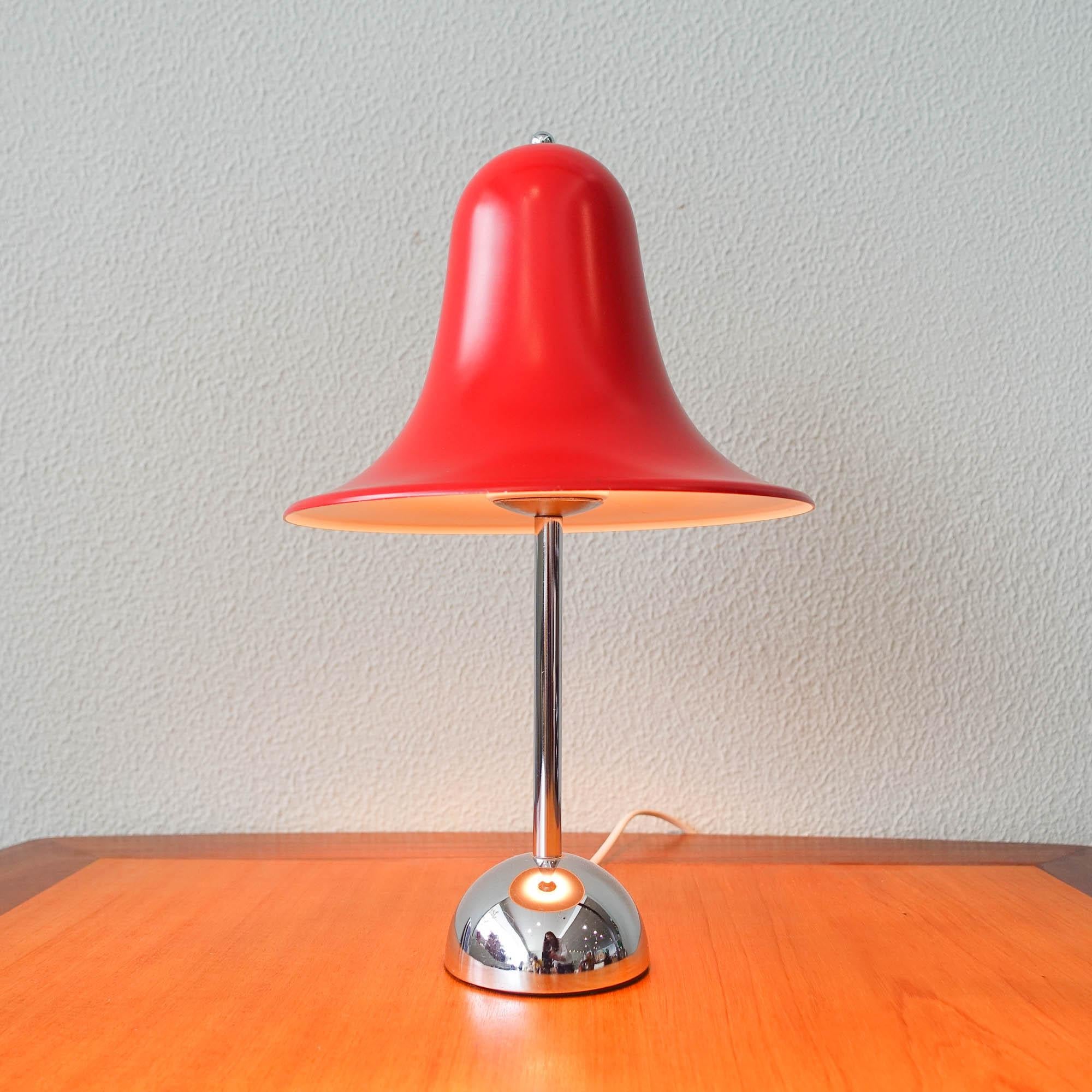 The Pantop D table lamp was designed by Verner Panton for Elteva Danmark A/S, in Denmark, during the 1980's. This lamp has a bell-shaped metal shade in red that is set in a chrome-plated base. Below is marked 