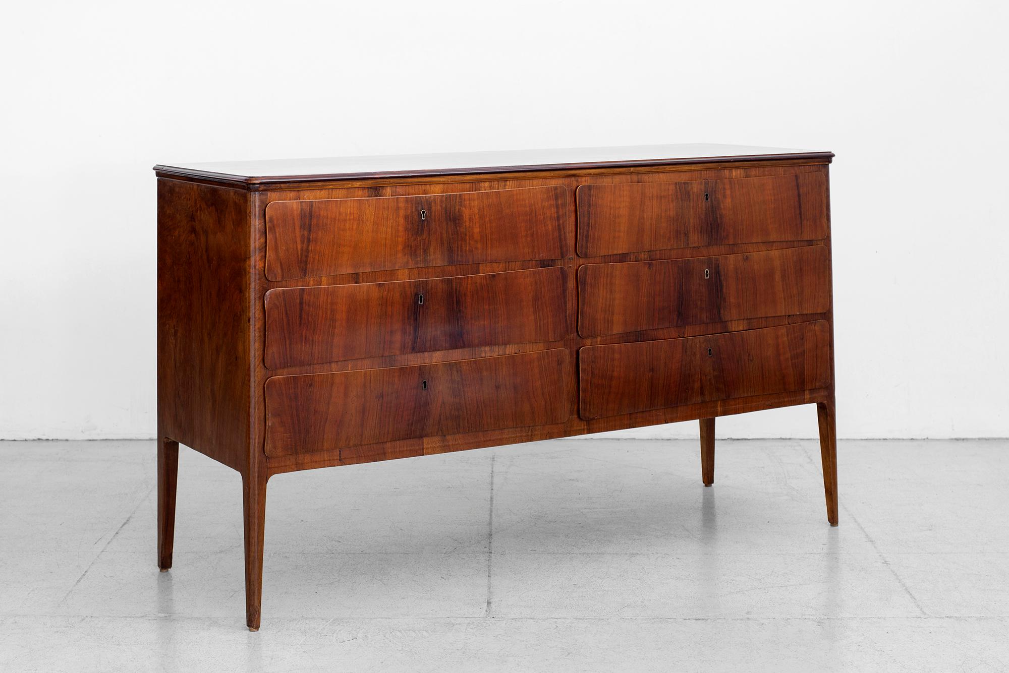 Gorgeous 1950s Italian chest of drawers attributed to Paola Buffa.
Cherry wood with six curved drawers and ornate brass hardware.
Tapered legs and beautiful grain to wood.
 