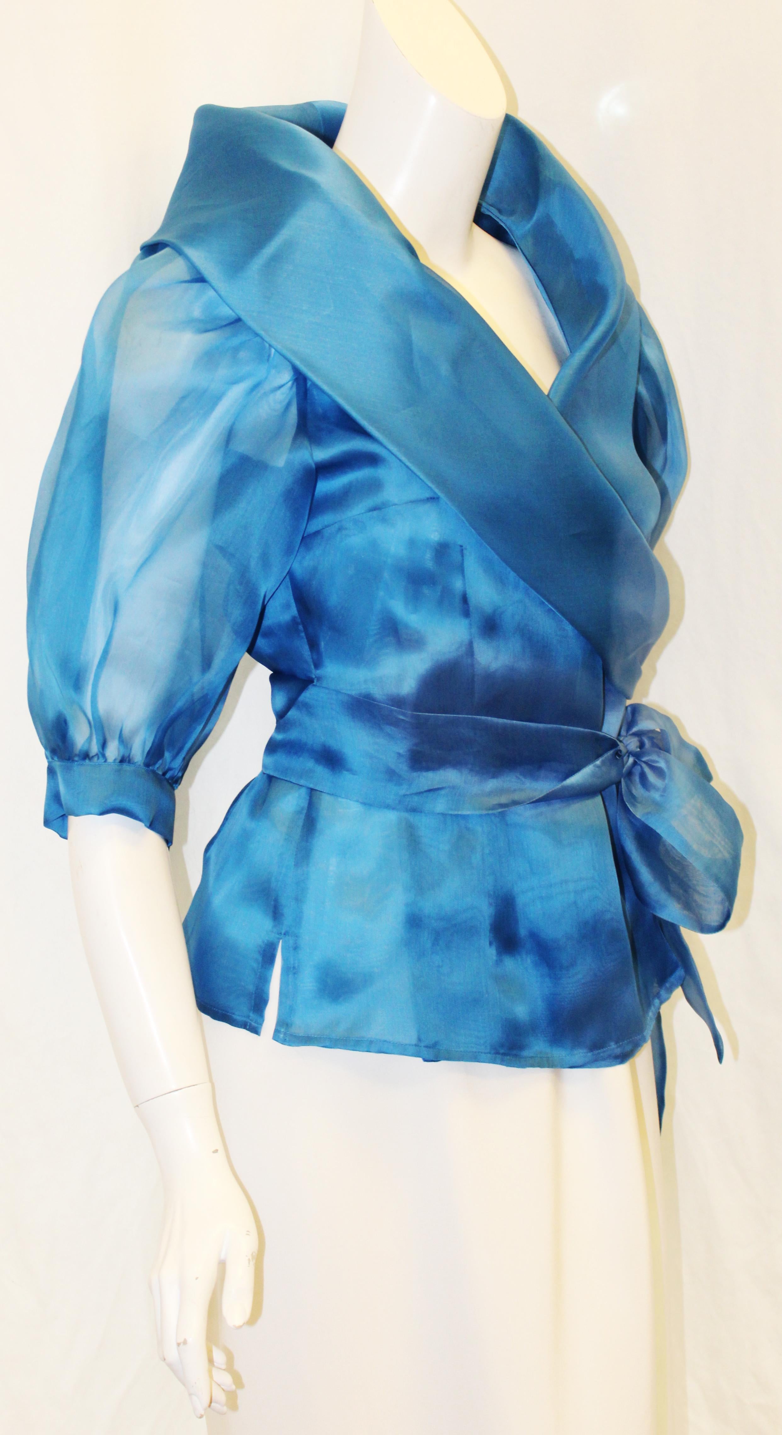 Paola Quadretti elegant blue silk organza wrap around blouse with 2 long sashes to cinch the waist.  This see through organza top in ocean blue tone is the perfect accessory for this season.  It can be dressed up with long white skirt or down with