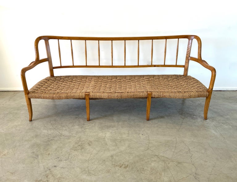 Incredible wood and rushed bench with beautiful scallop shaped woven rush seat, curved back with carved arms and tapered legs. 
Incredible piece.
