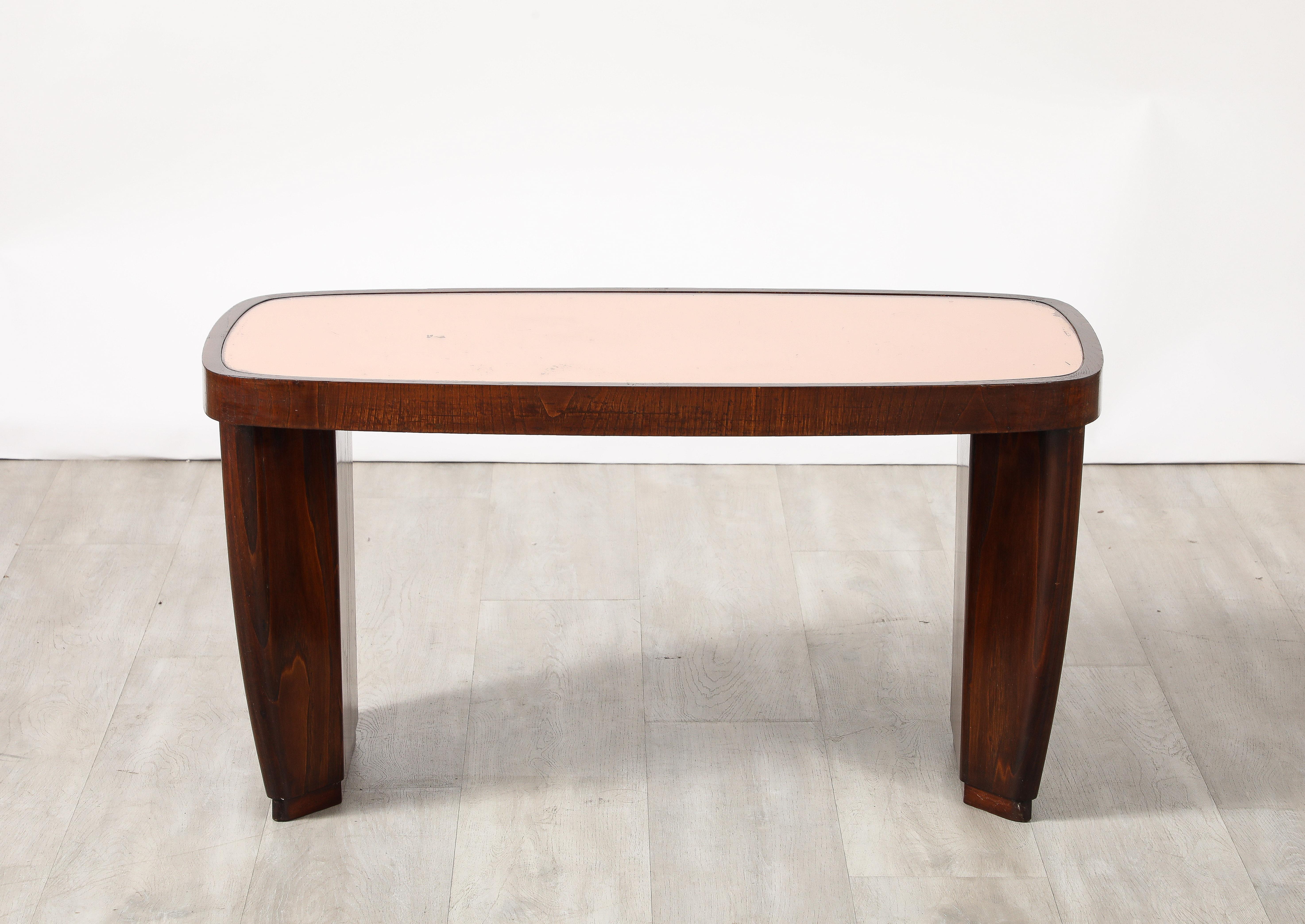 Table à cocktail en noyer attribuée à Paolo Buffa ; les panneaux latéraux avec un centre rectangulaire et des coins inclinés, supportant le plateau en verre couleur or rose.  

Paolo Buffa (né en 1903 à Milan - mort en 1970) était un créateur de