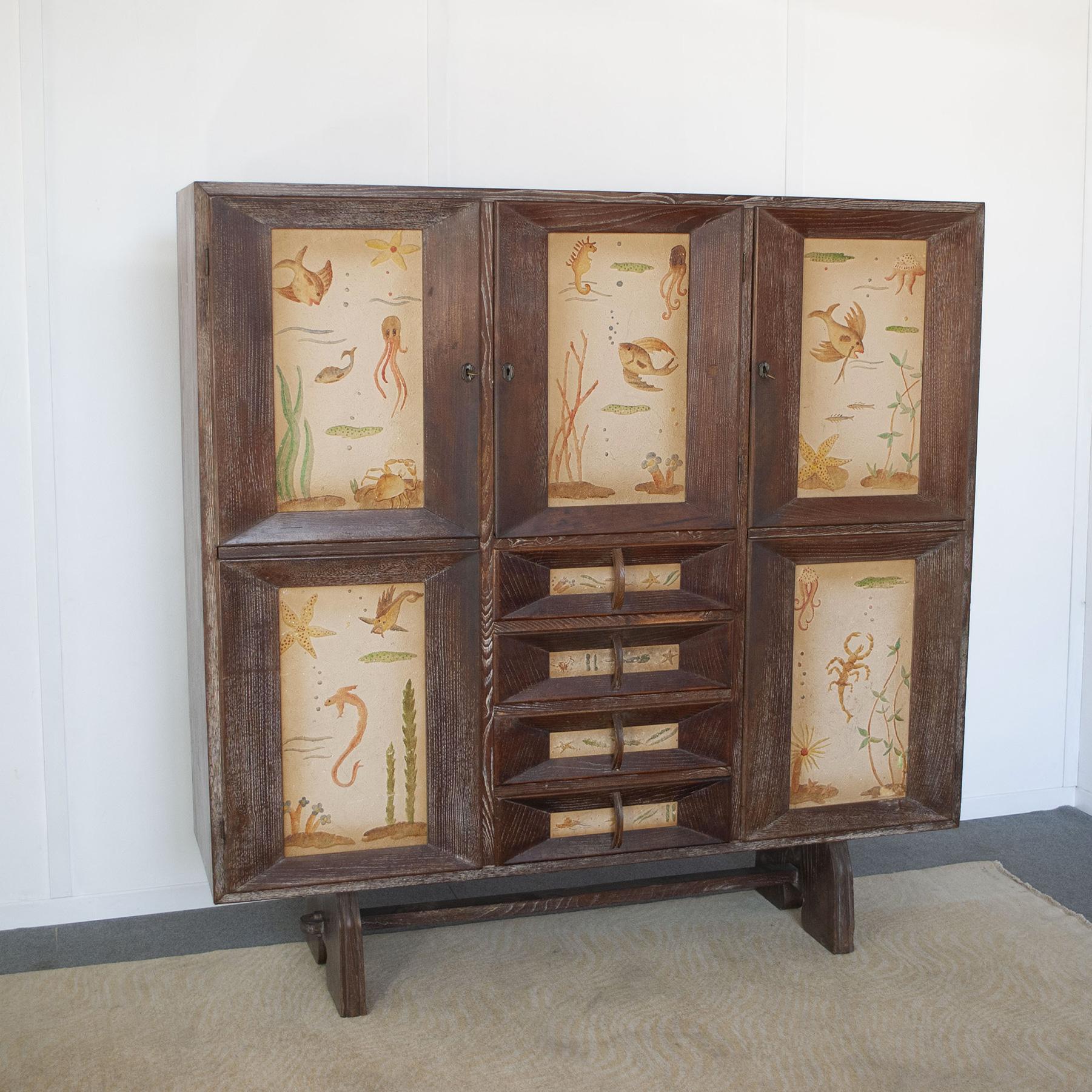 Paolo Buffa  cabinet in beech wood with three  lockable doors and four drawers. The doors and drawers have relief decorations of marine environments. Dassi production late 1940s.