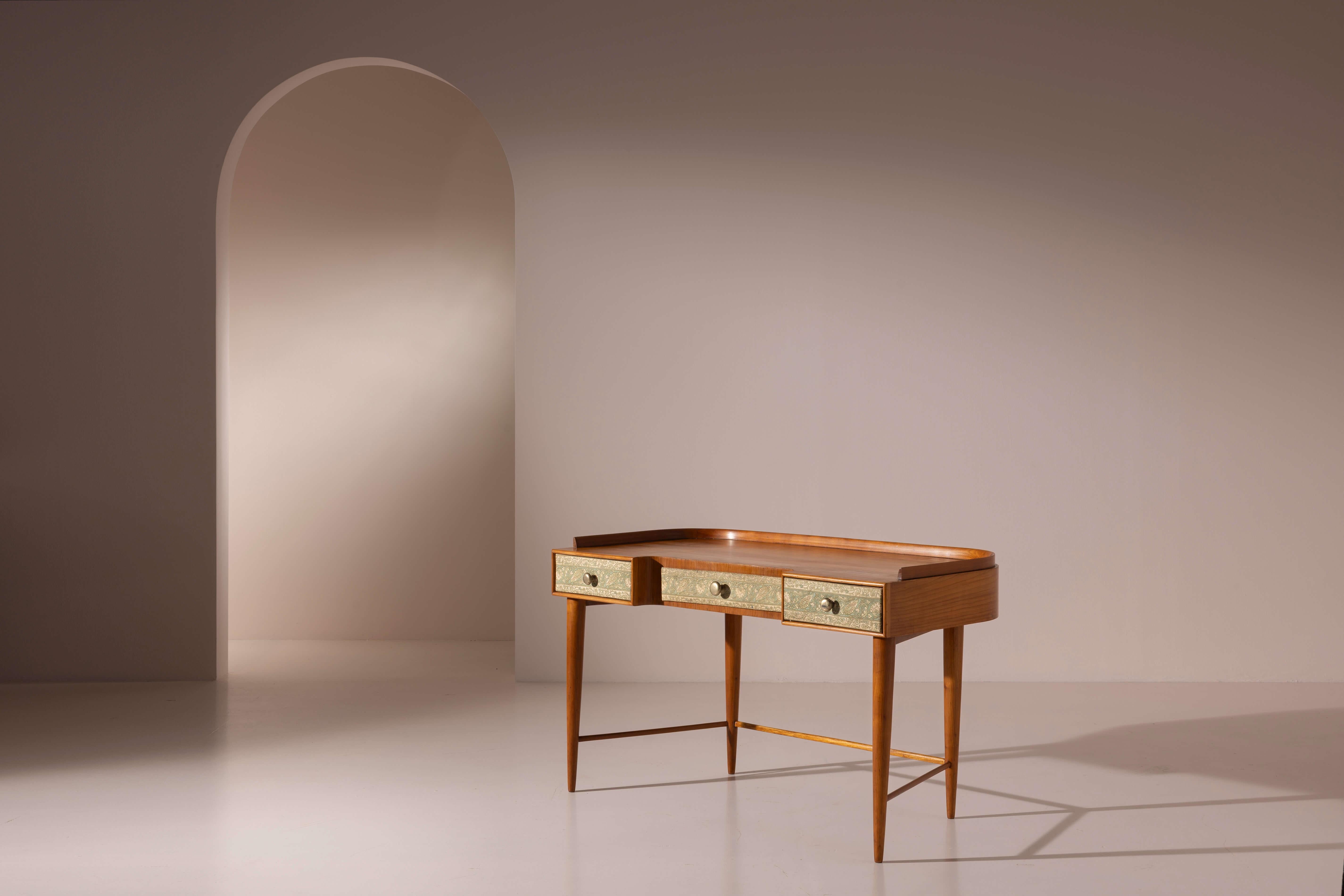 Un elegante scrittoio in ciliegio con cassetti rivestiti in tessuto, design di Paolo Buffa, manifattura italiana, anni '40

Questo pezzo raffinato merita di essere osservato da ogni angolazione per apprezzarne appieno il design. Vista frontalmente,