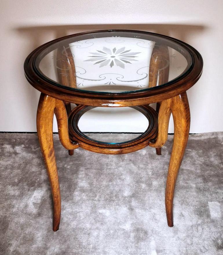 Elegant and particular Italian coffee table in cherry wood; the top is enriched by a round glass with delicate and refined engravings; exceptional is the graceful and harmonious design of the legs that are connected to each other to support the