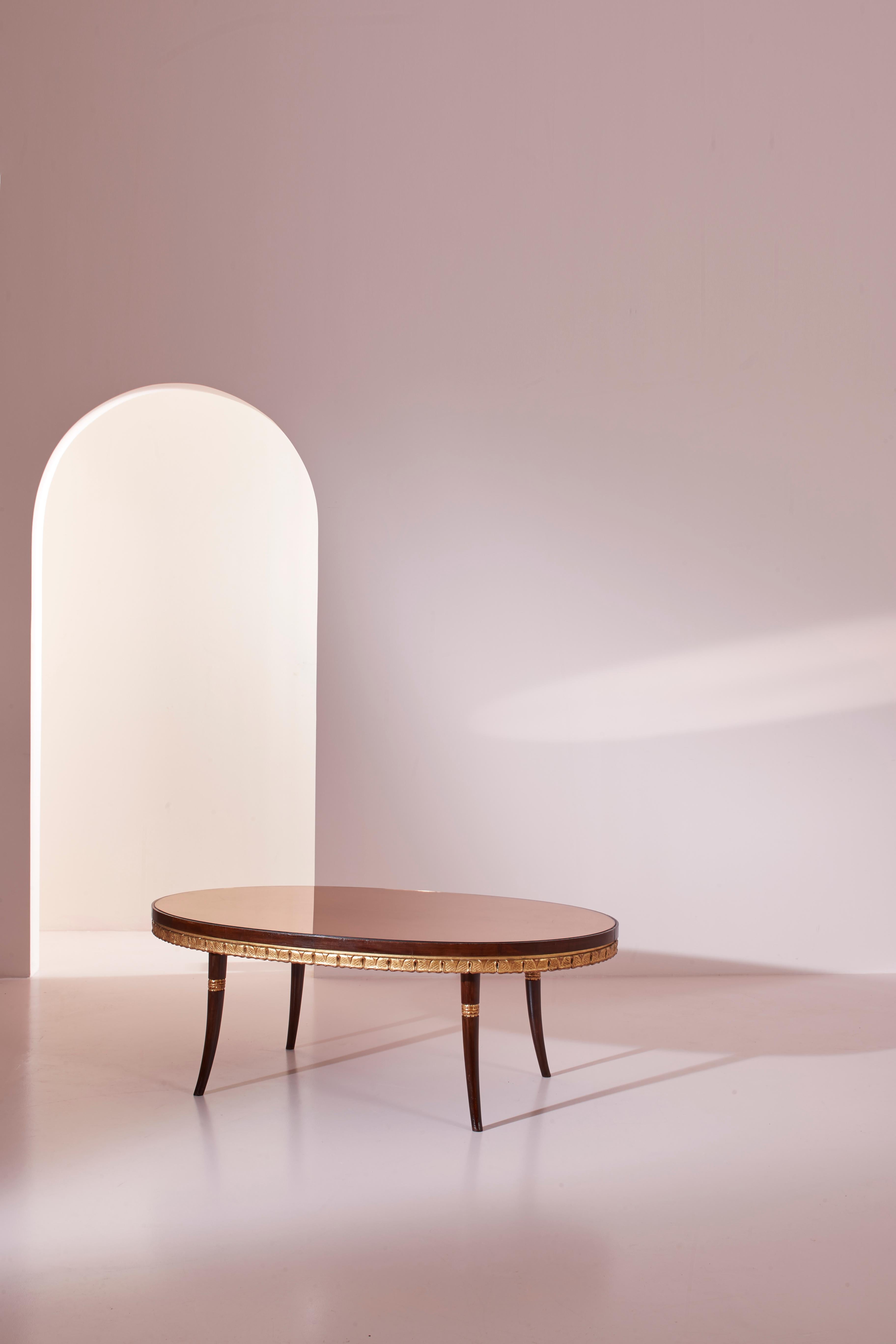 Une magnifique table basse au goût classique, fabriquée en bois peint et doré avec un plateau en verre miroir. Produite en Italie d'après le design de Paolo Buffa, cette petite table date du milieu des années 1950.

Avec une forme ovale et quatre