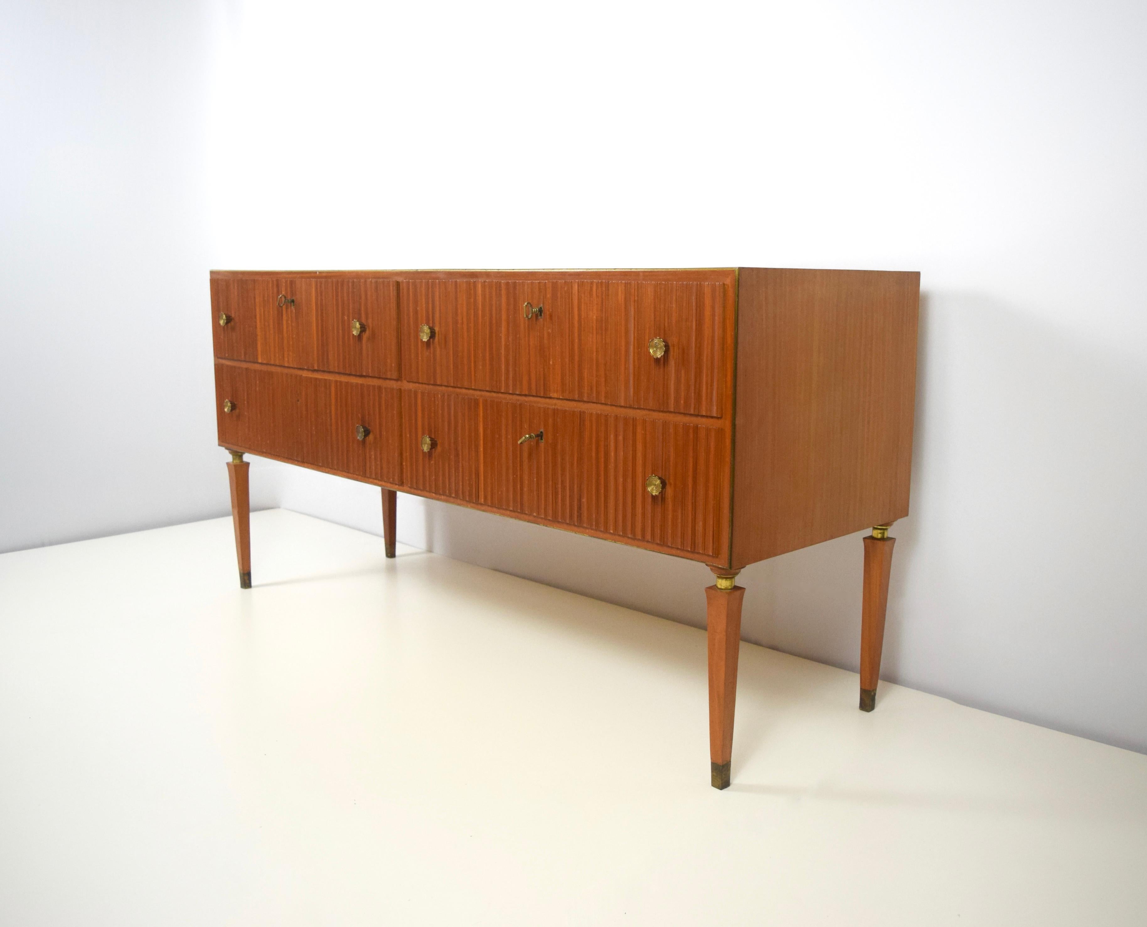 Absolutely stunning and elegant credenza with mahogany and brass designed by Paolo Buffa from Italy, 1940s or 1950s. The credenza has four drawers and beautiful details. There is a little brass line all around the credenza. The handles have a flower