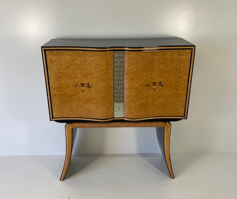 This precious and unique bar cabinet was produced in Italy in the 40s by Paolo Buffa.
The doors are in maple burl with two inlays in various woods which create a typical Art Deco design.
The profiles on the legs are in solid maple while the