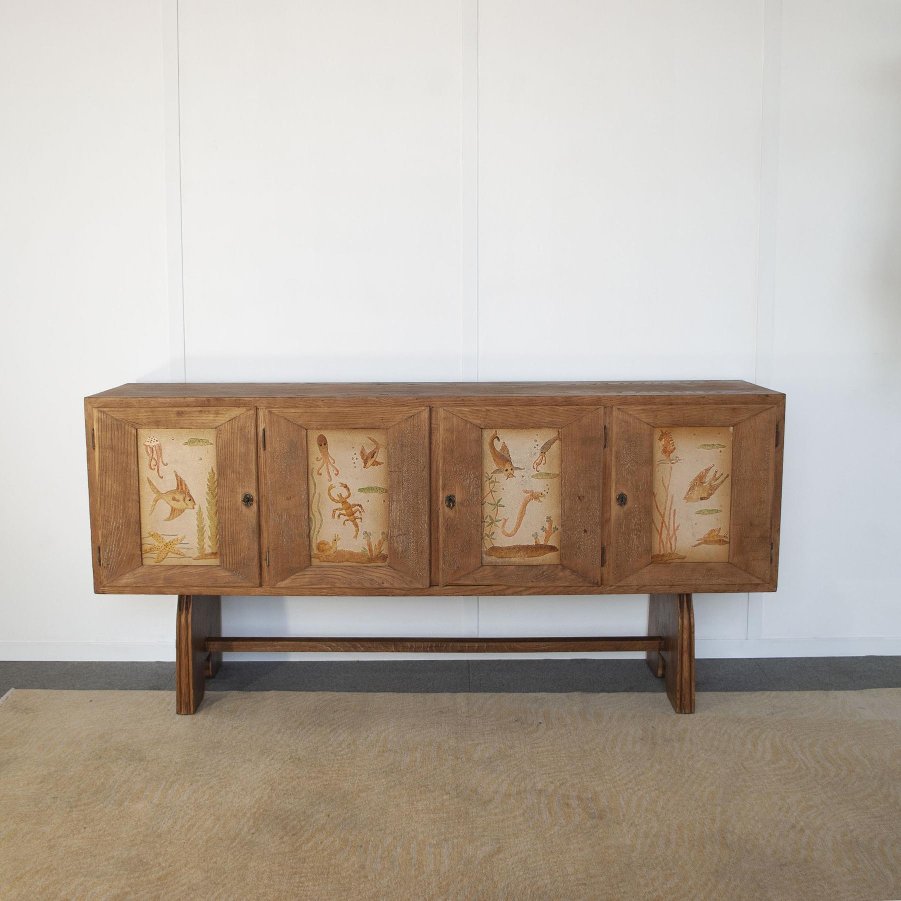 Paolo Buffa  sideboard in beech wood with four lockable doors. The doors have relief decorations of marine environments. Dassi production late 1940s.
