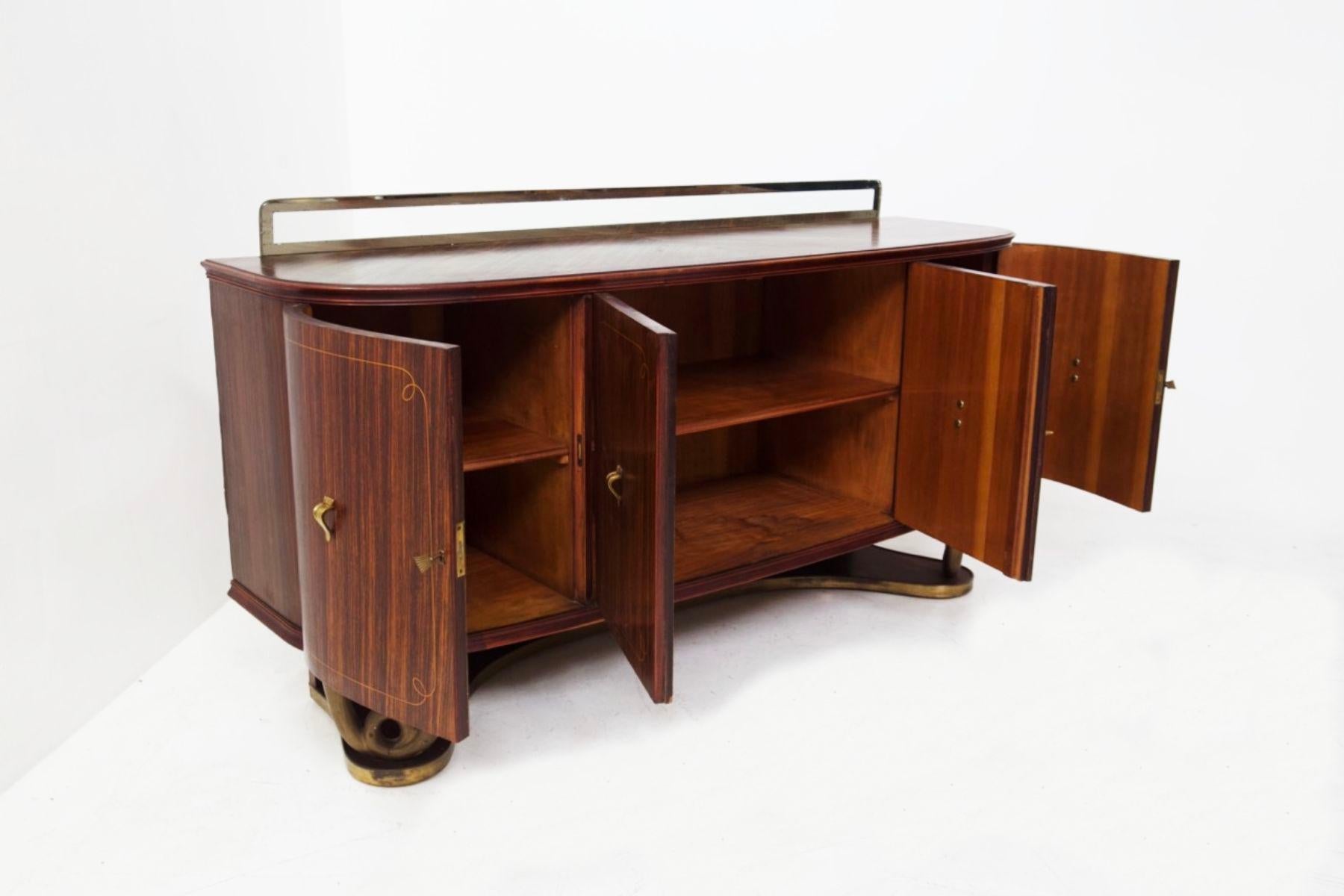 A splendid Mid-Century sideboard attributed to the great 1950s designer Paolo Buffa.
The sideboard is entirely made of the finest wood with beautiful soft and evident grain.
The base is made of wood with a brass frame. Two eccentric feet form a very