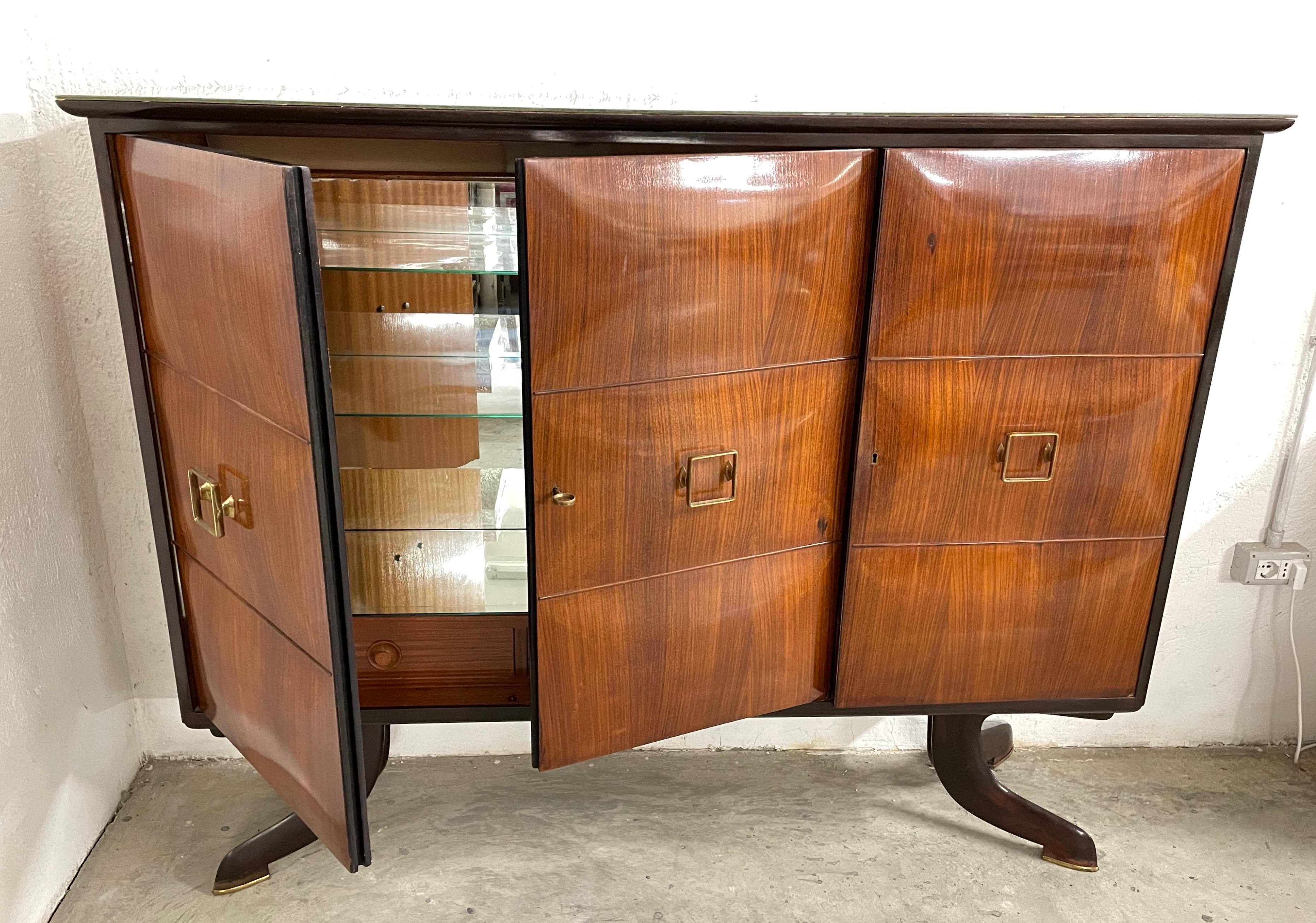 Exceptional dry bar cabinet with mirrors from the mid-century Paolo Buffa. This storage cabinet was produced in Italy during the 1950s

The front body has three solid veneered wood doors with rounded legs panels. The cabinet is veneered on all