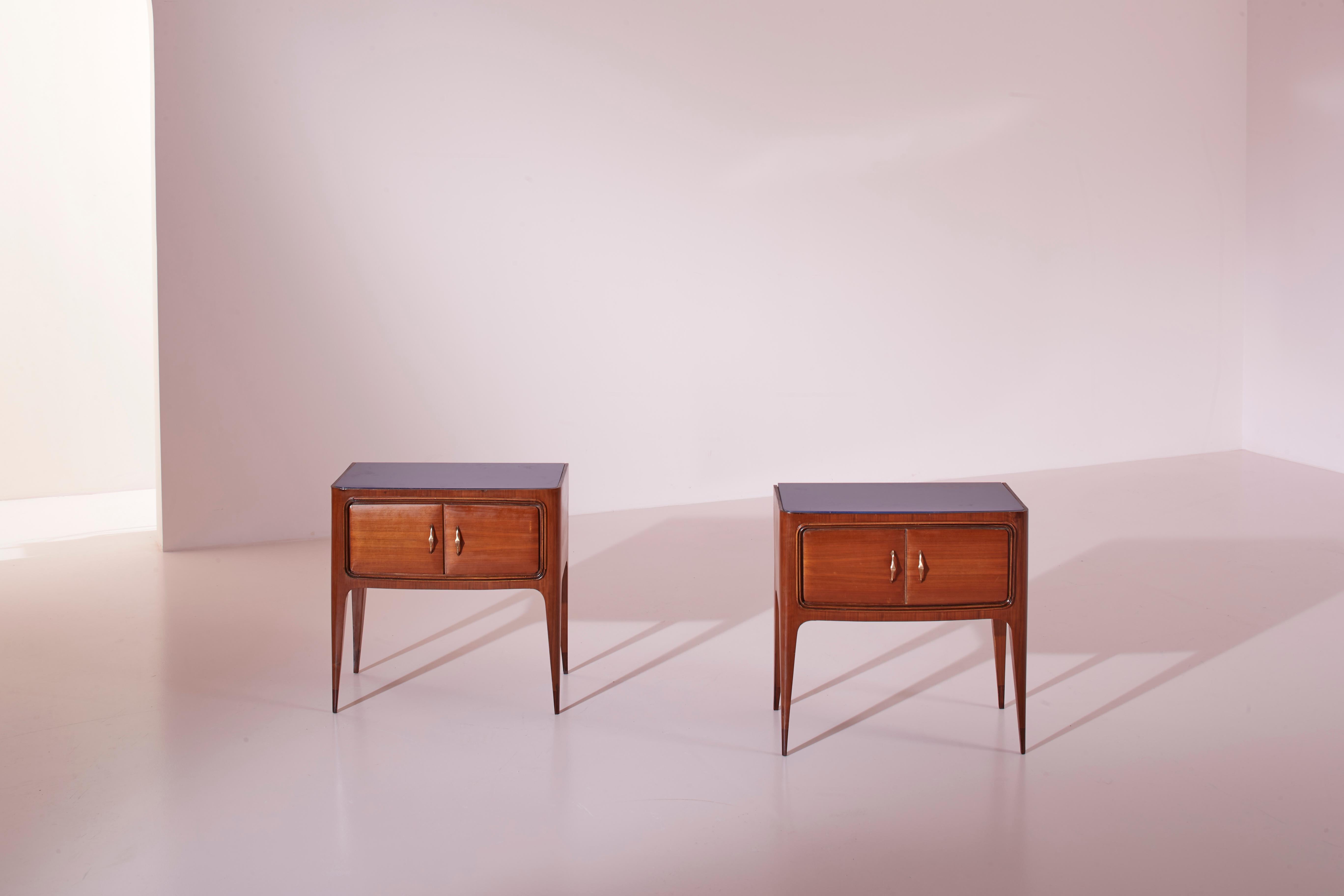 A pair of wooden and glass bedside tables, Italian craftsmanship from the 1950s, designed by Paolo Buffa.

Characterized by two small doors framed by delicate moldings, these Italian bedside tables from the 1950s showcase the finesse of Paolo