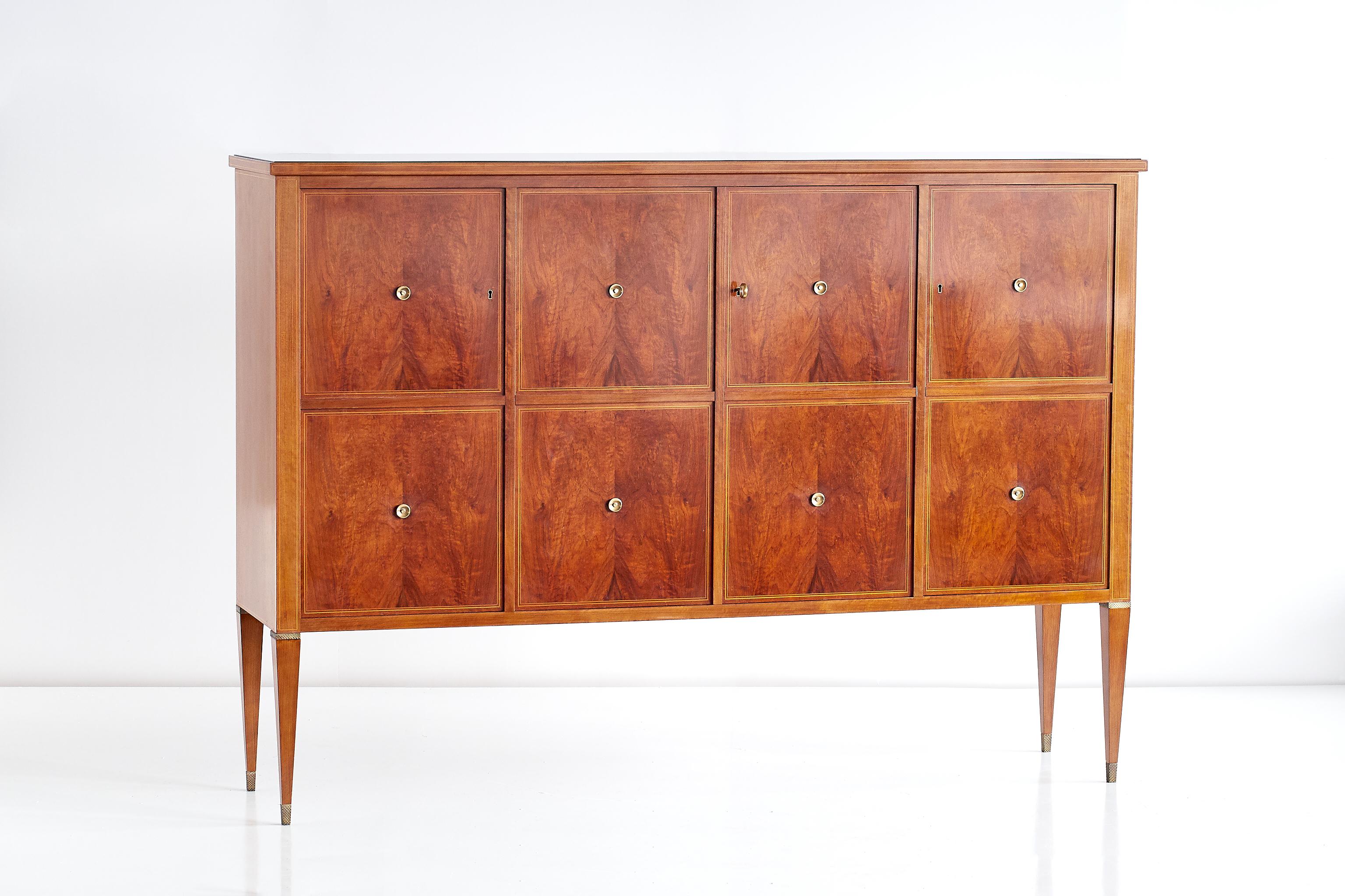 This large four-door panelled cabinet was designed by Paolo Buffa in the early 1950s. The composition of the striking grain of the eight mahogany veneered panels and the decorative brass details give the cabinet a refined and elegant appearance. The